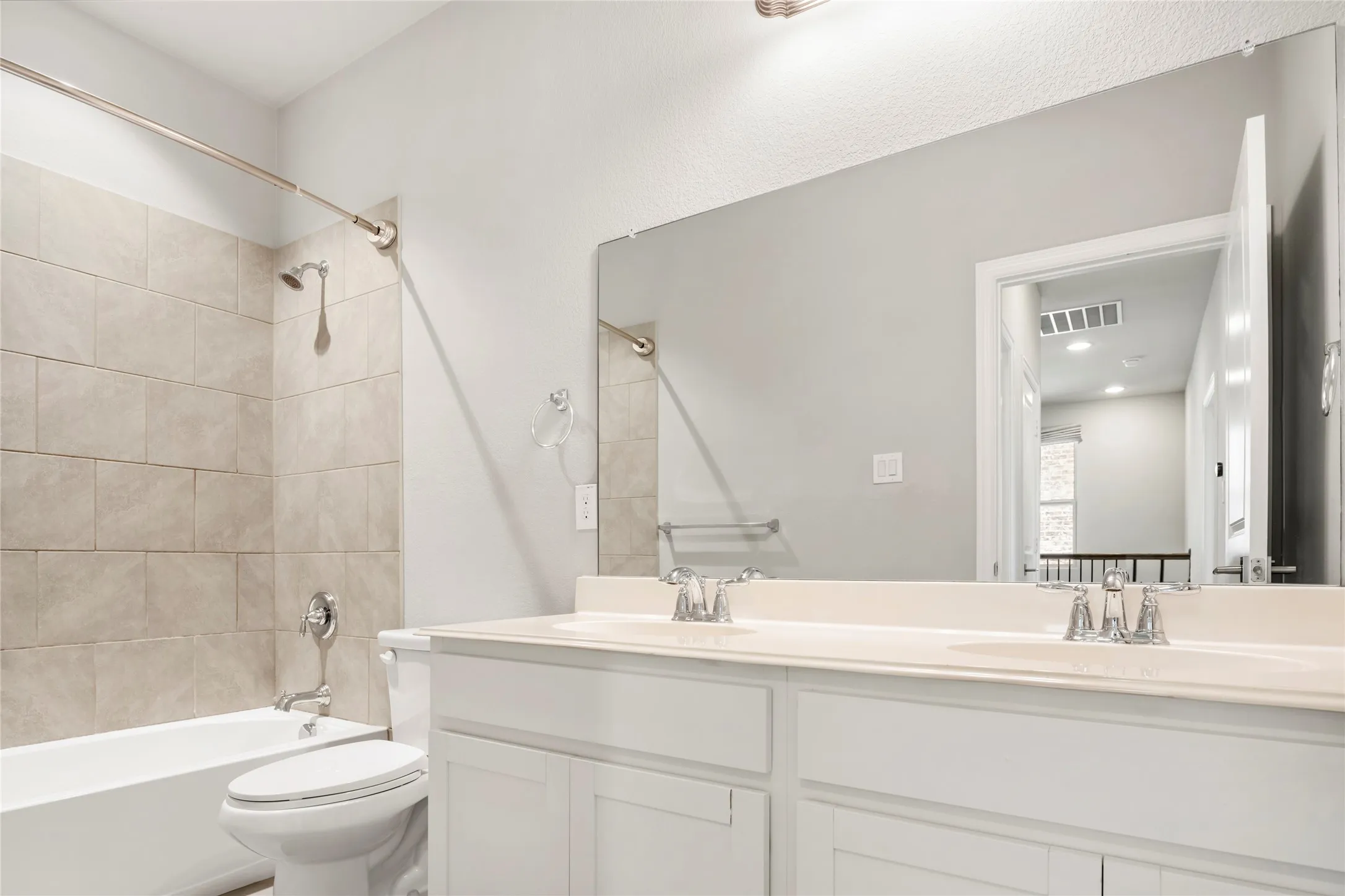 Bathroom featuring a dual vanity with white cabinetry, integrated sinks, and chrome fixtures