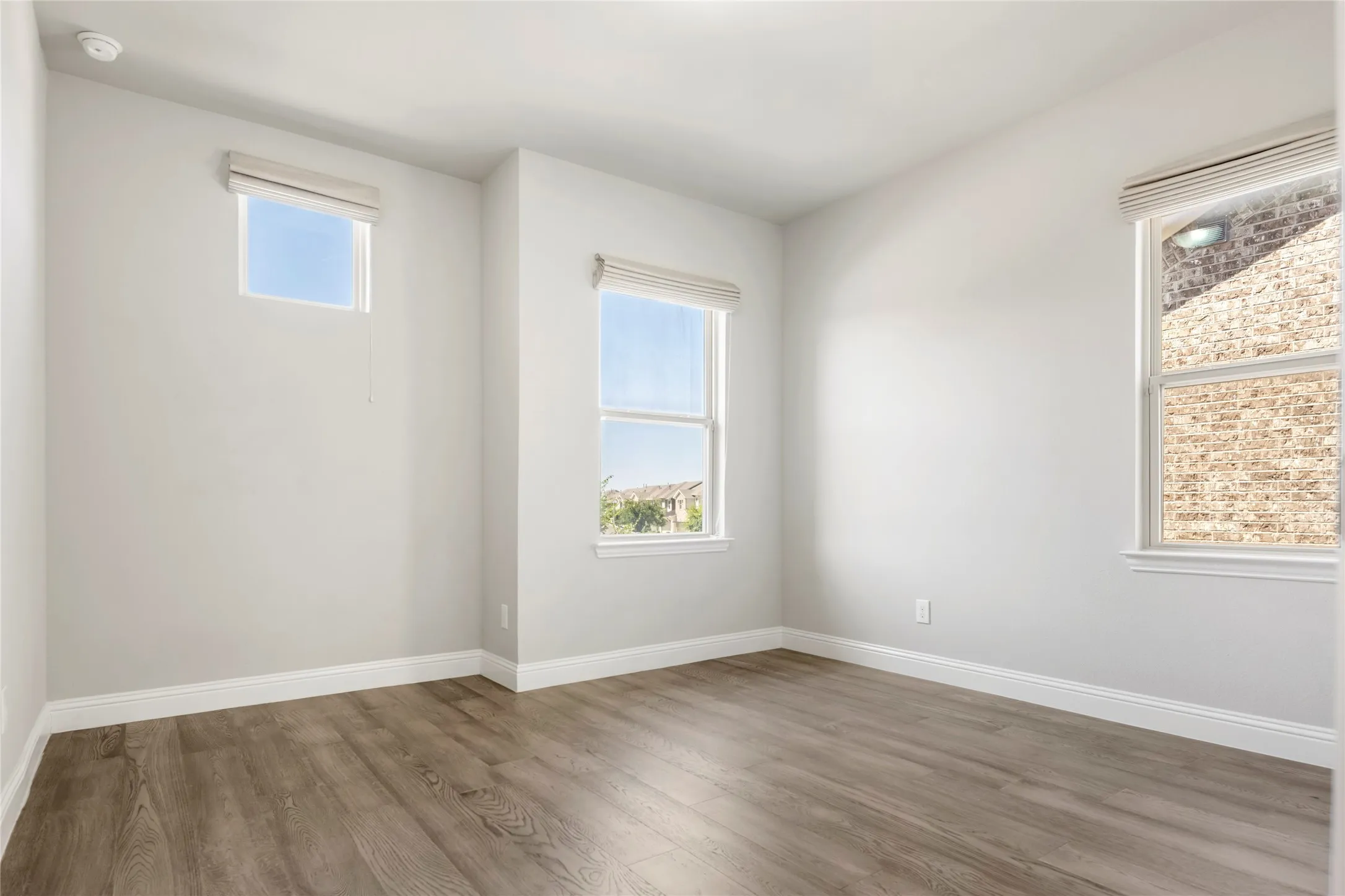 Bright room featuring wood-finish flooring, white baseboards, and light-toned walls