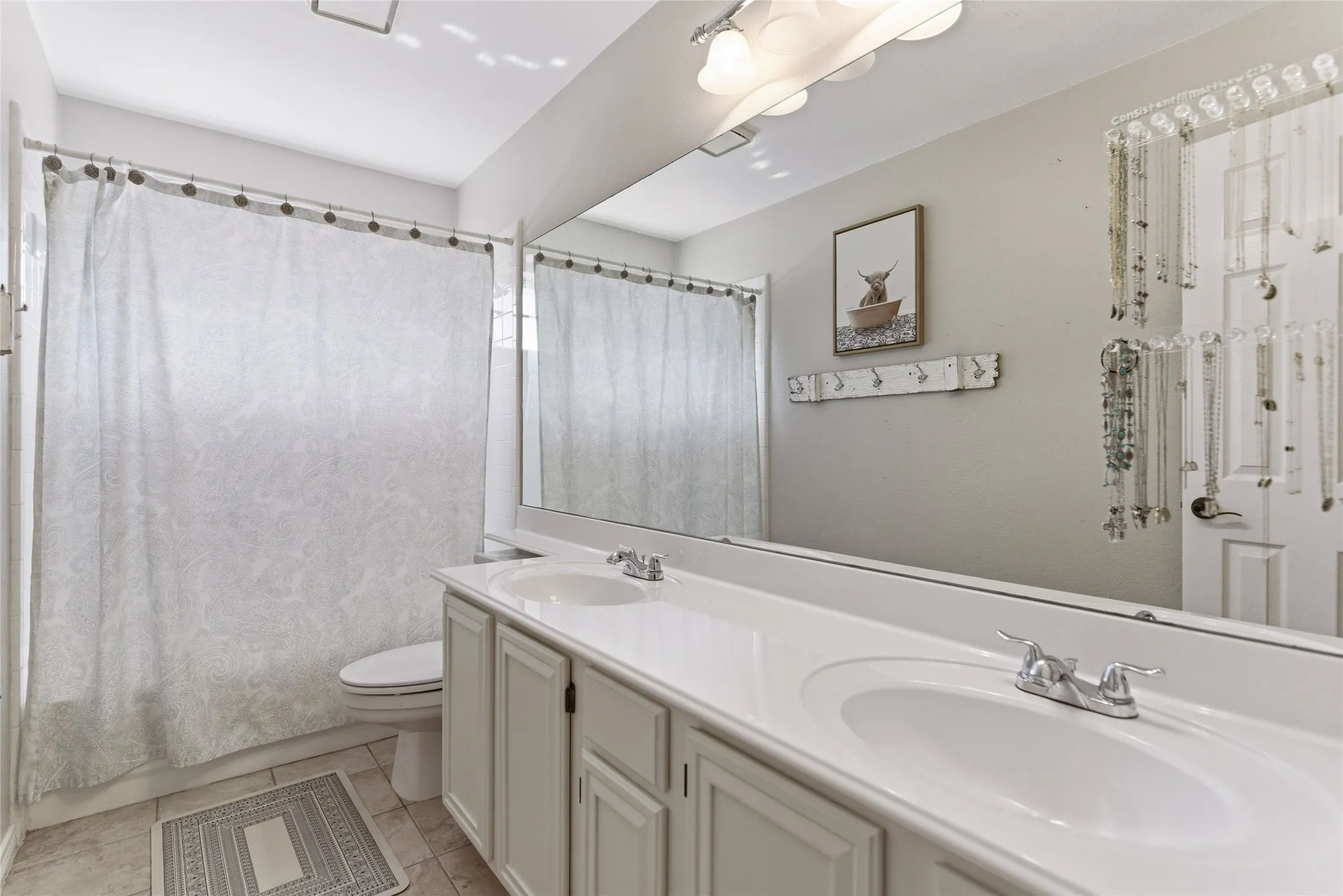 Bathroom featuring a dual vanity with integrated sinks, chrome faucets, and white cabinetry