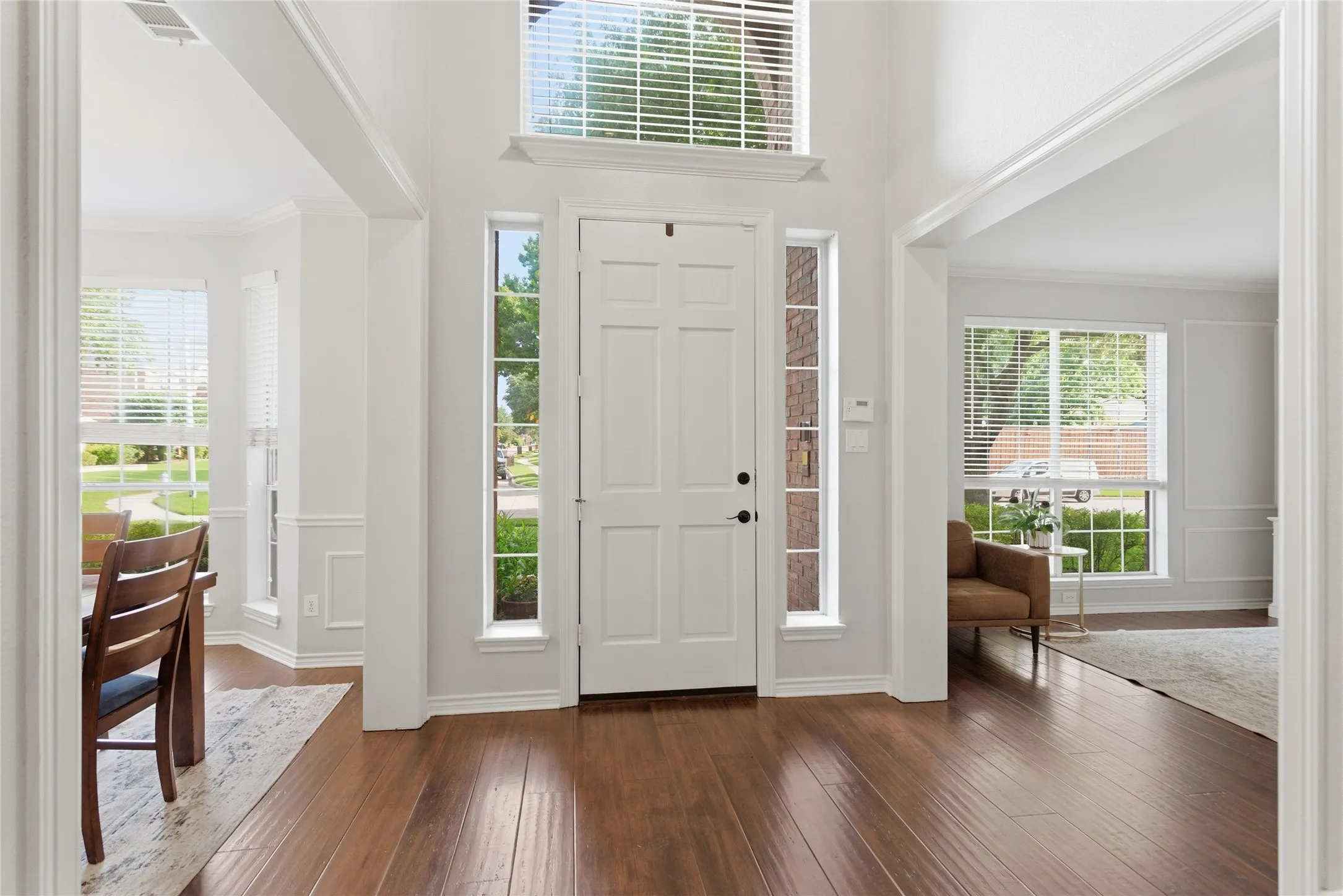 Entryway featuring wood-finish flooring, a paneled front door with side lite windows, and an overhead transom window
