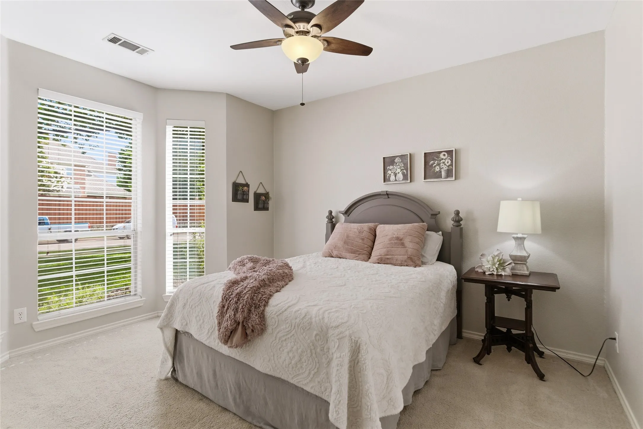 Carpeted room featuring a ceiling fan with integrated lighting, multiple windows with blinds, and light-toned walls