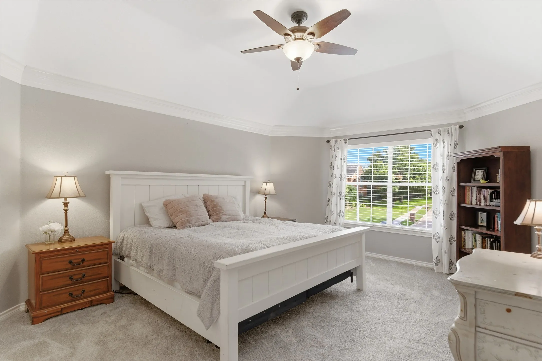 Spacious room featuring vaulted ceilings, crown molding, a large window with blinds, carpeted flooring, and a built-in ceiling fan with lighting
