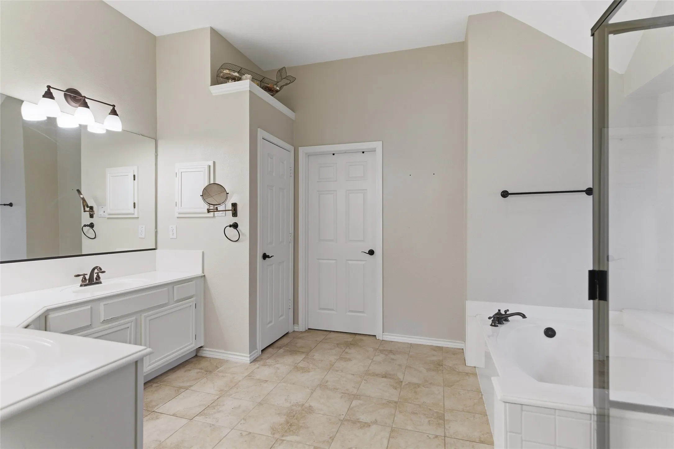 Bathroom featuring a large vanity with ample countertop space, a built-in tub, a separate shower enclosure, and tiled flooring
