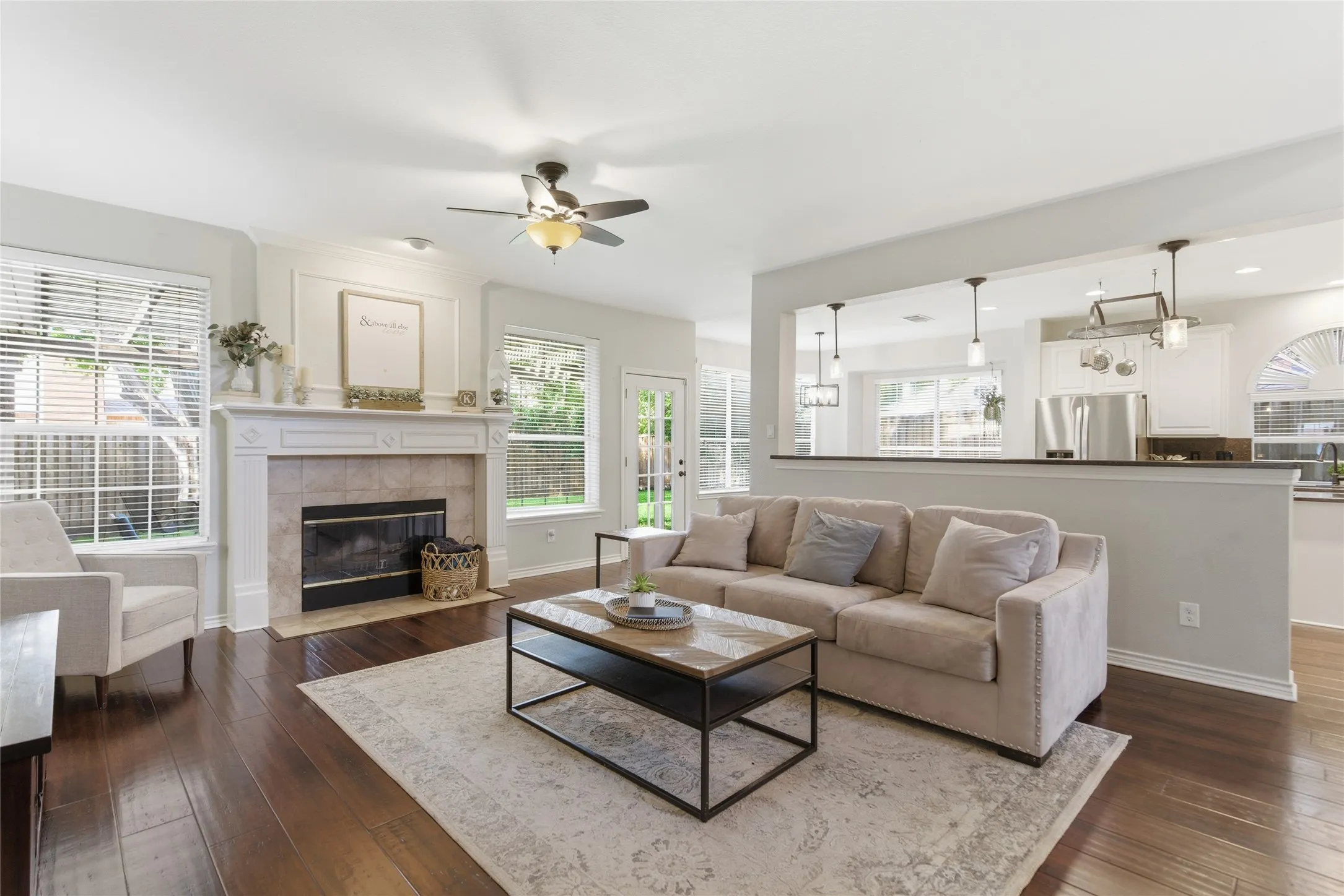 Living area featuring wood-finish flooring, a decorative fireplace with a tile surround and mantel, and white interior trim