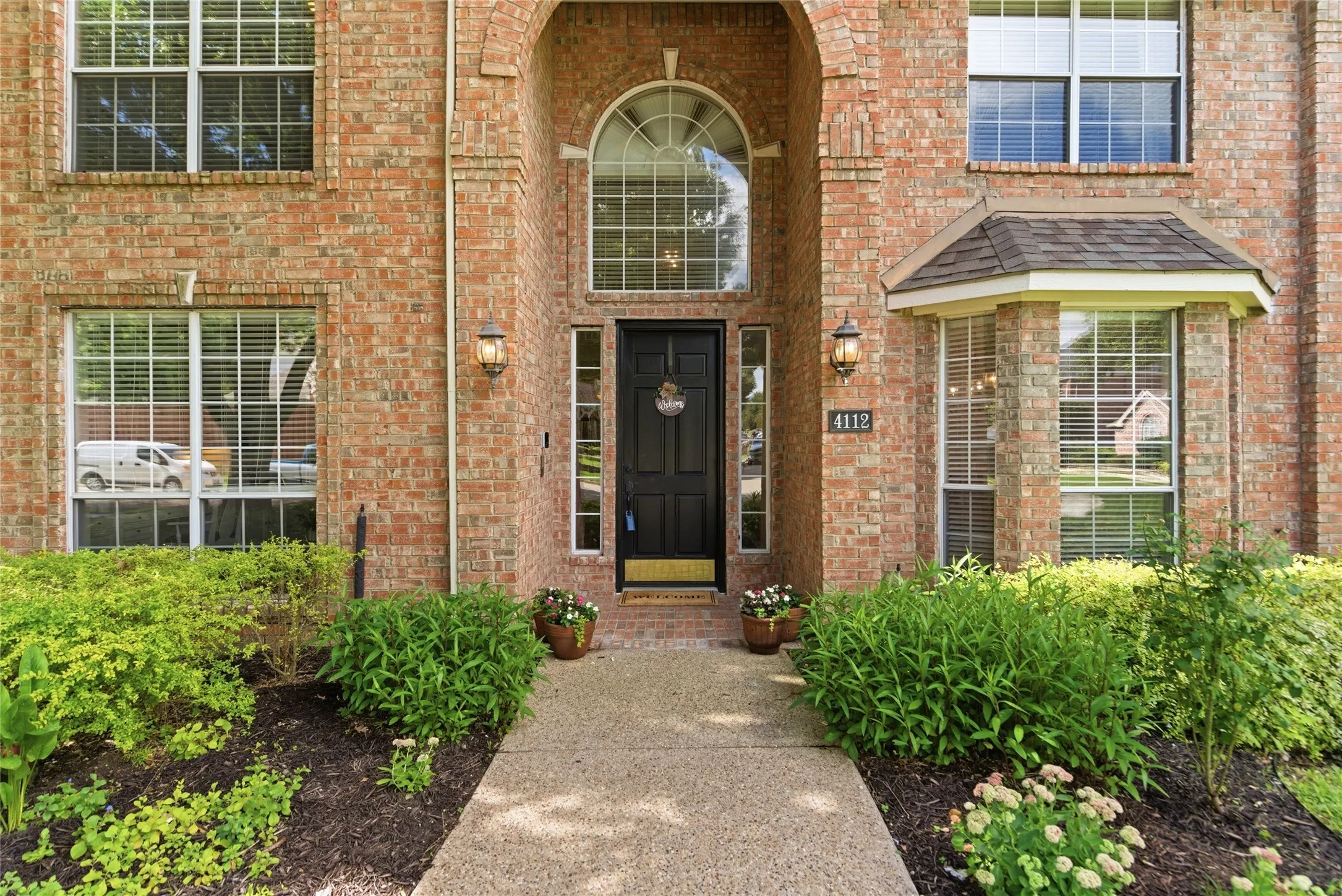Brick exterior with an arched entry, a black front door, and an arched transom window