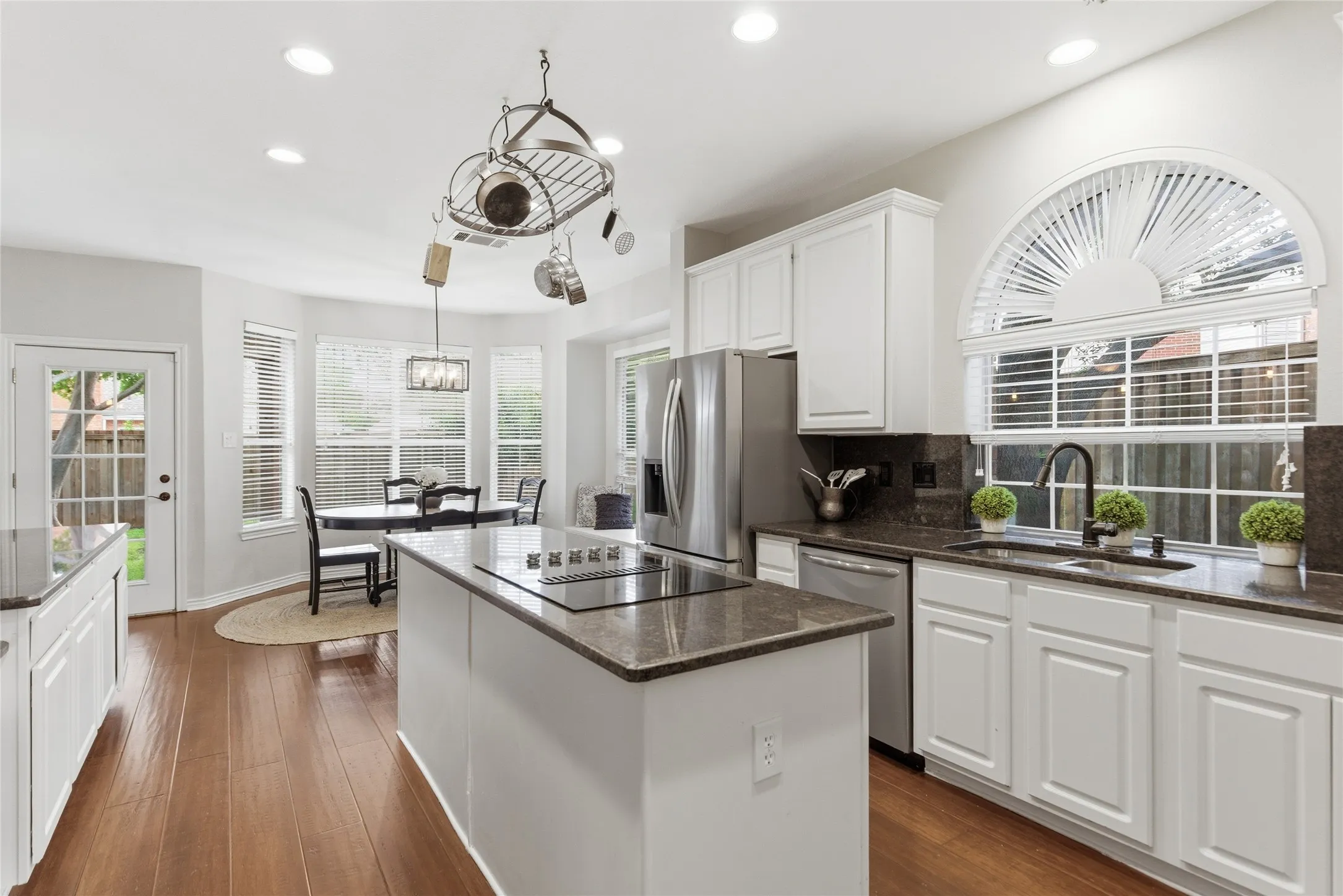 Contemporary kitchen featuring wood-finish flooring and white cabinetry