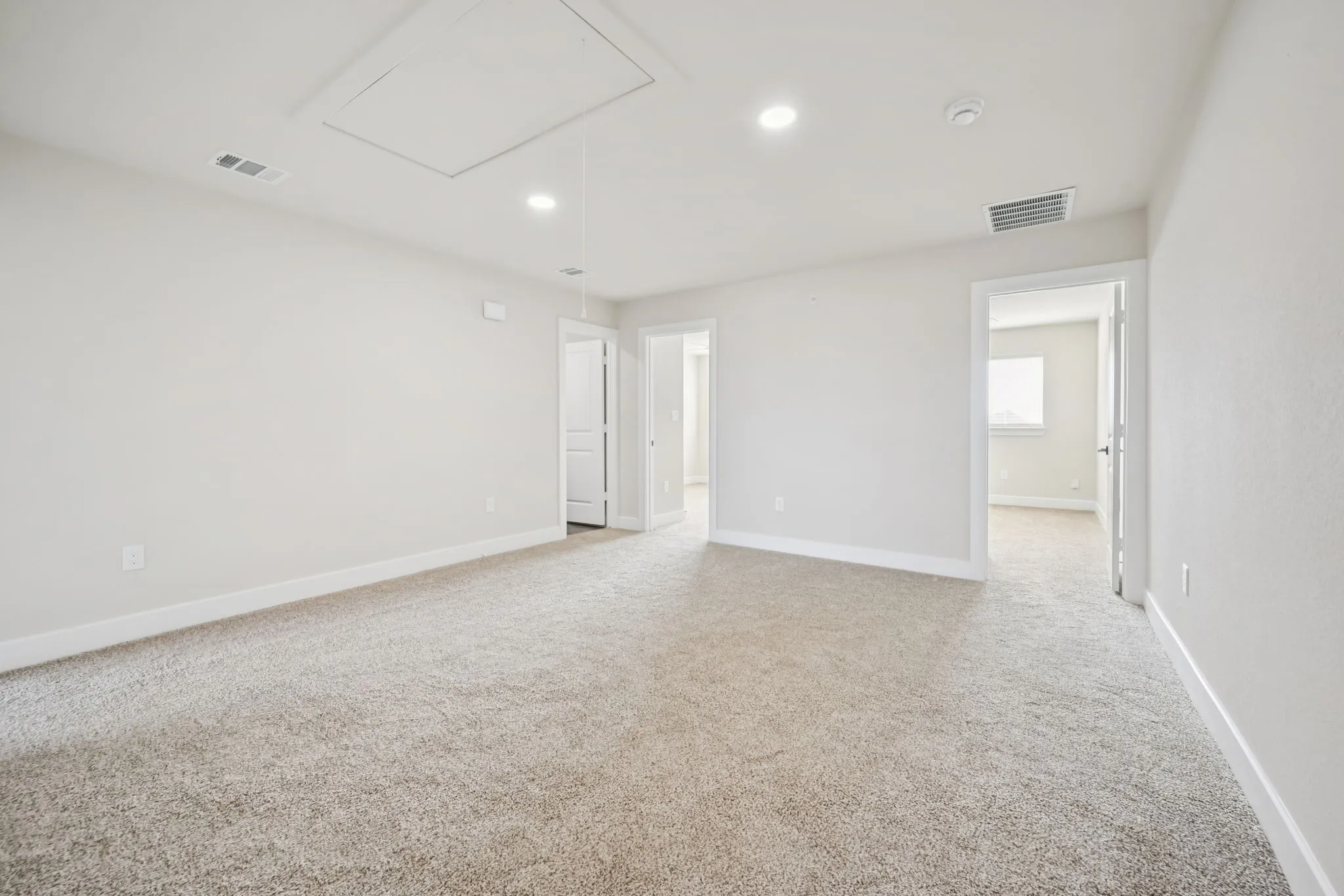 Carpeted secondary living space featuring light-toned walls, recessed lighting, and multiple doorways