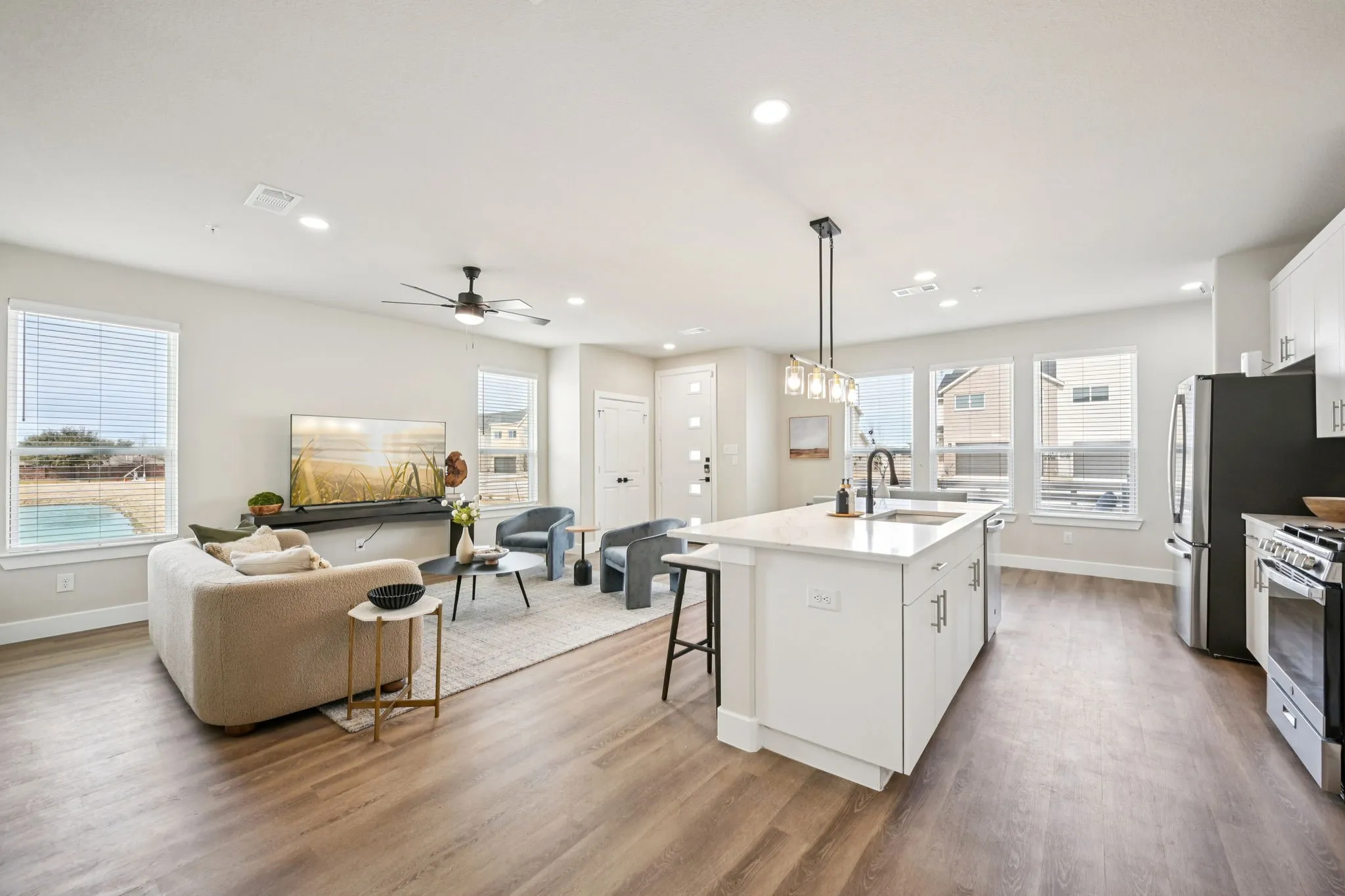 Open-concept living area featuring wood-finish flooring, recessed lighting, and a contemporary ceiling fan