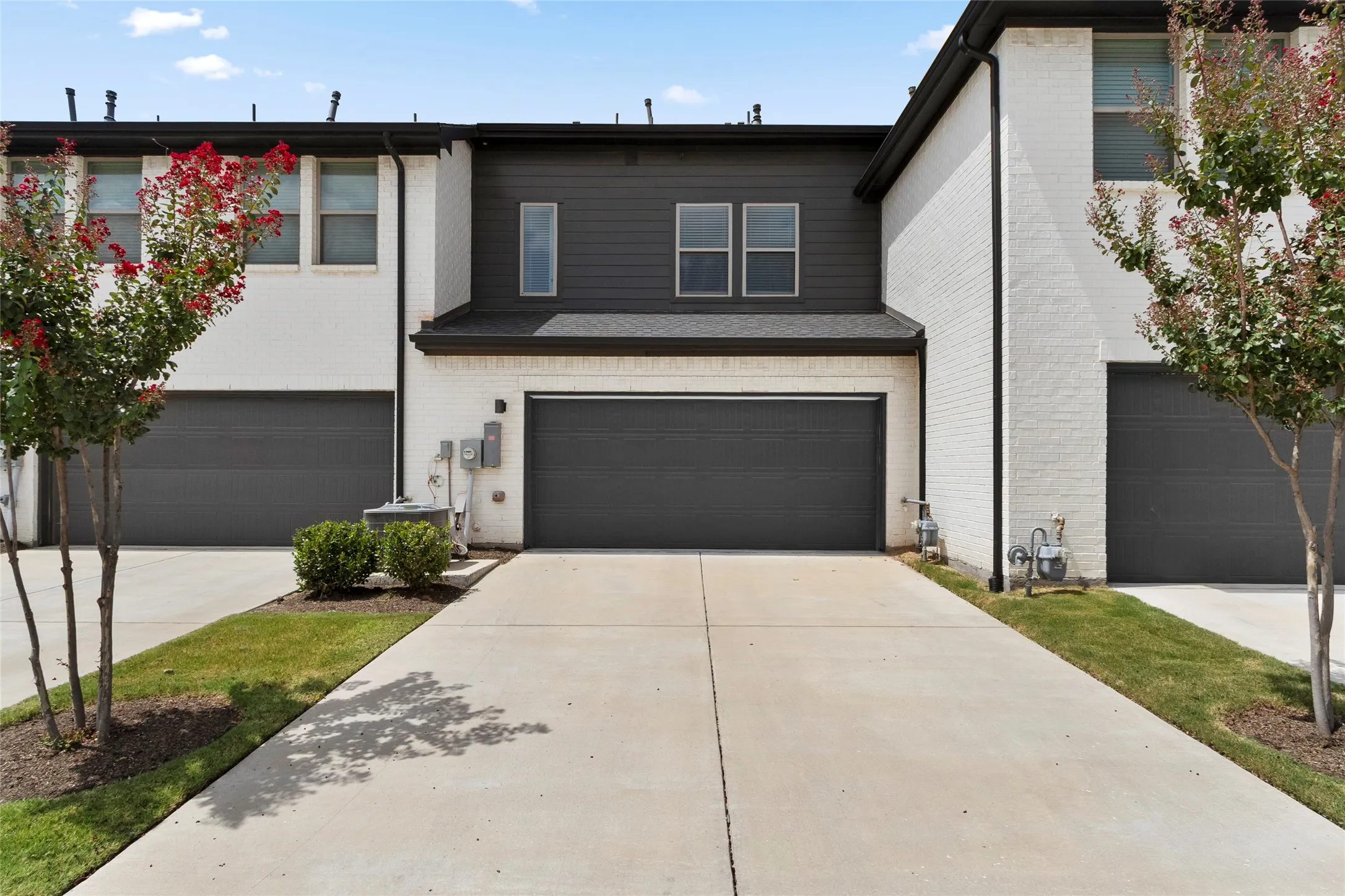 Modern townhome exterior featuring a white brick facade and dark horizontal siding