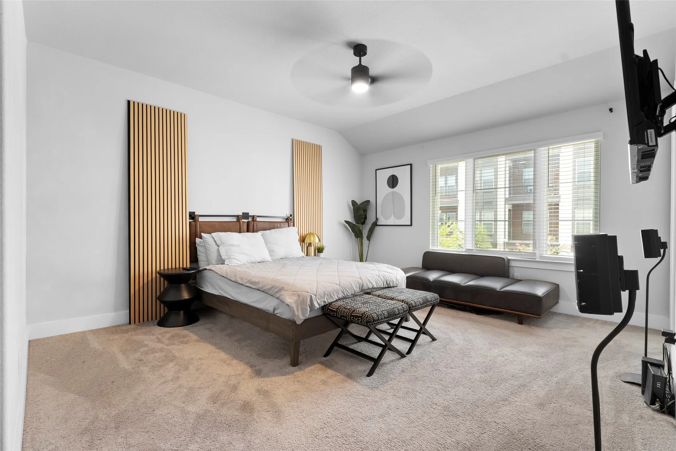 Spacious room featuring light-colored carpeting, a large three-panel window with blinds, and white walls