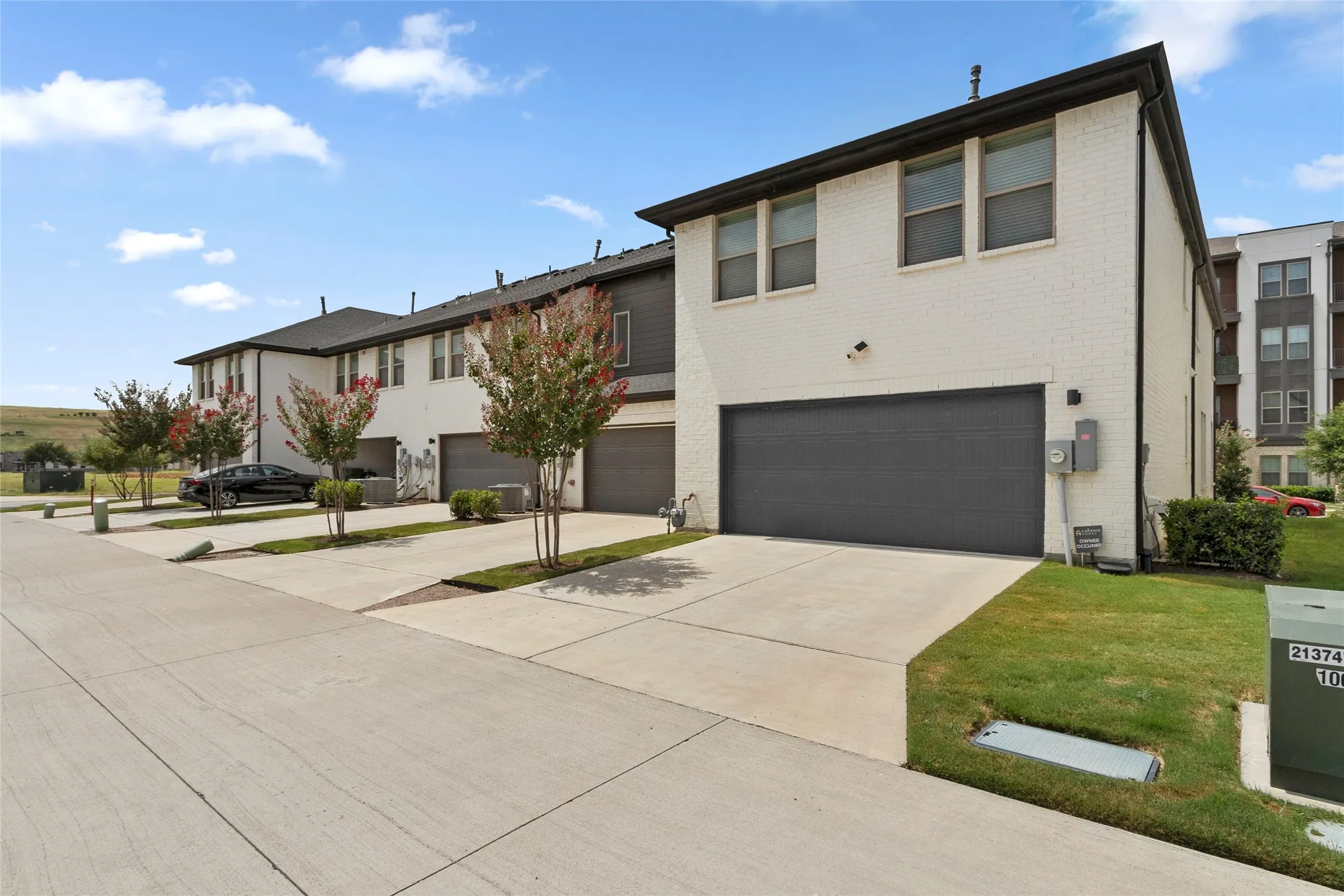 Modern townhome exterior featuring white brick siding and a dark gray garage door