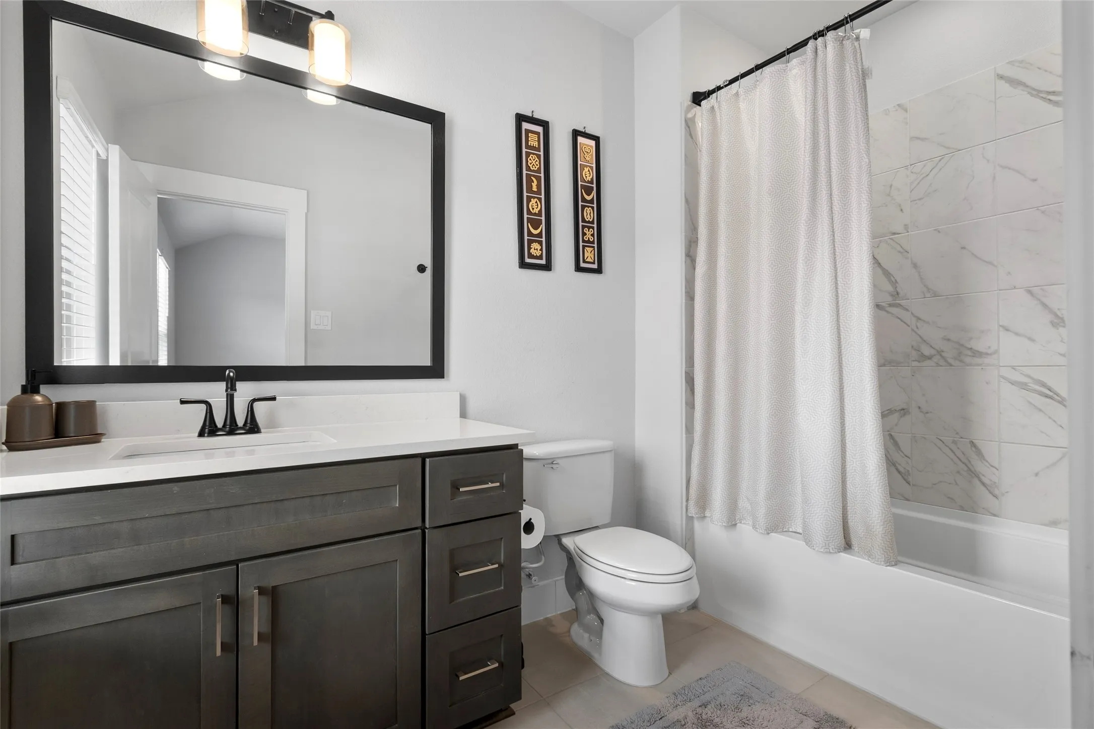 Contemporary bathroom featuring a vanity with dark wood-finish cabinetry, a white countertop, and a rectangular undermount sink with a matte black faucet