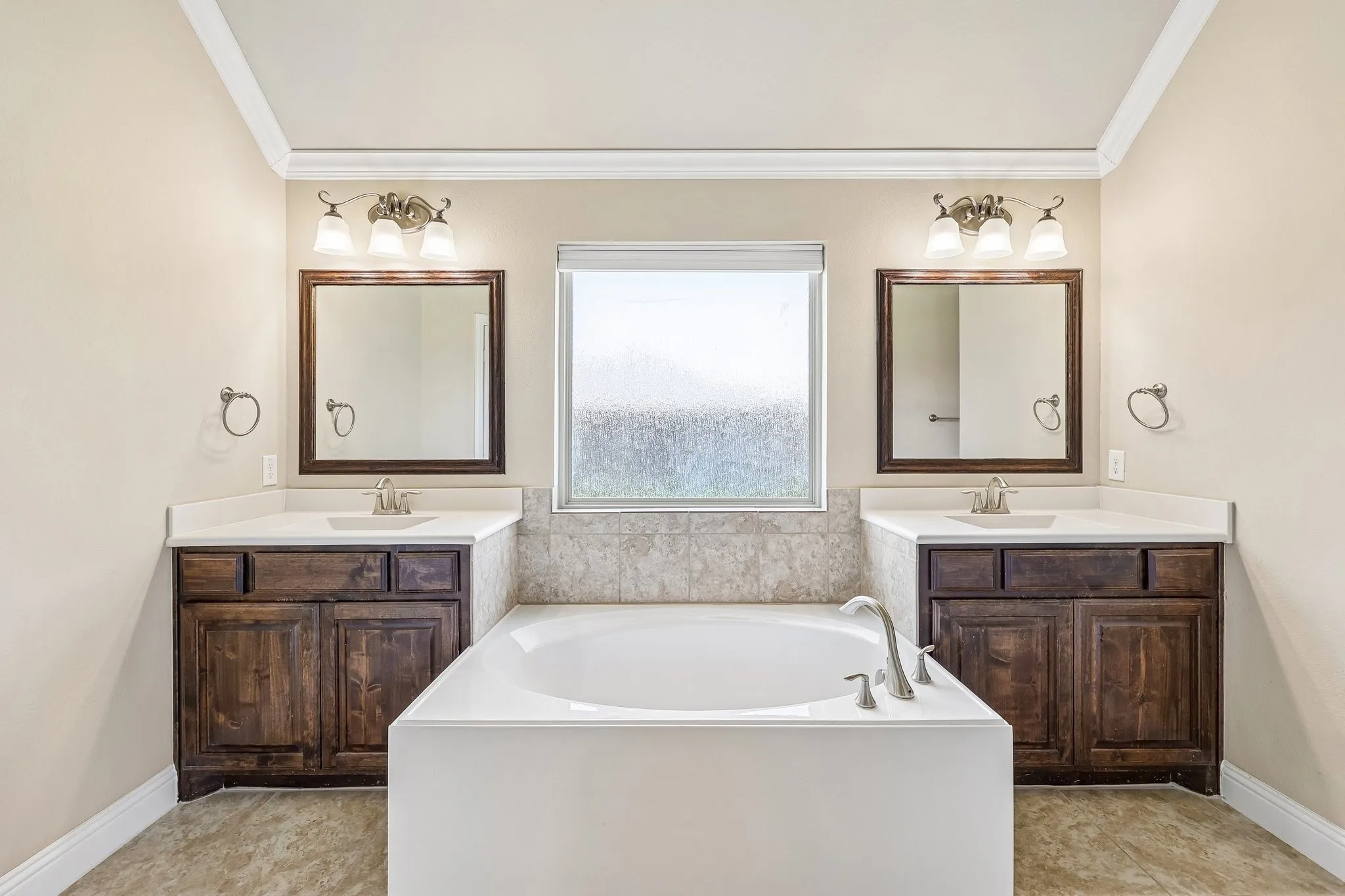 Soaking tub with brushed nickel fixtures, bordered by a tiled surround