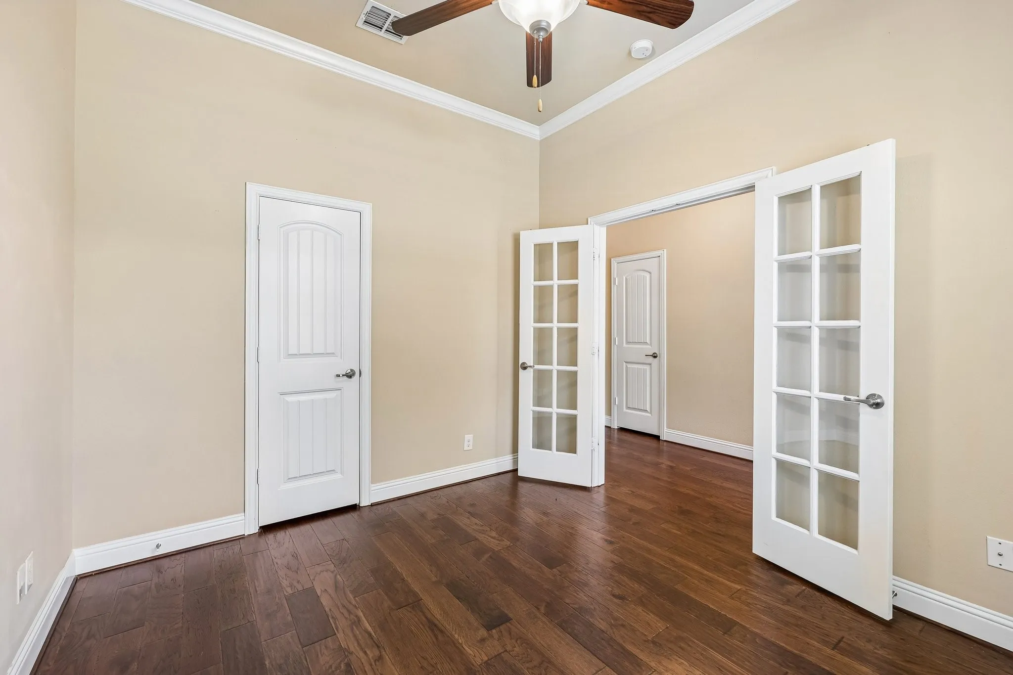 Room featuring dark wood-finish flooring, light-toned walls, and white crown molding