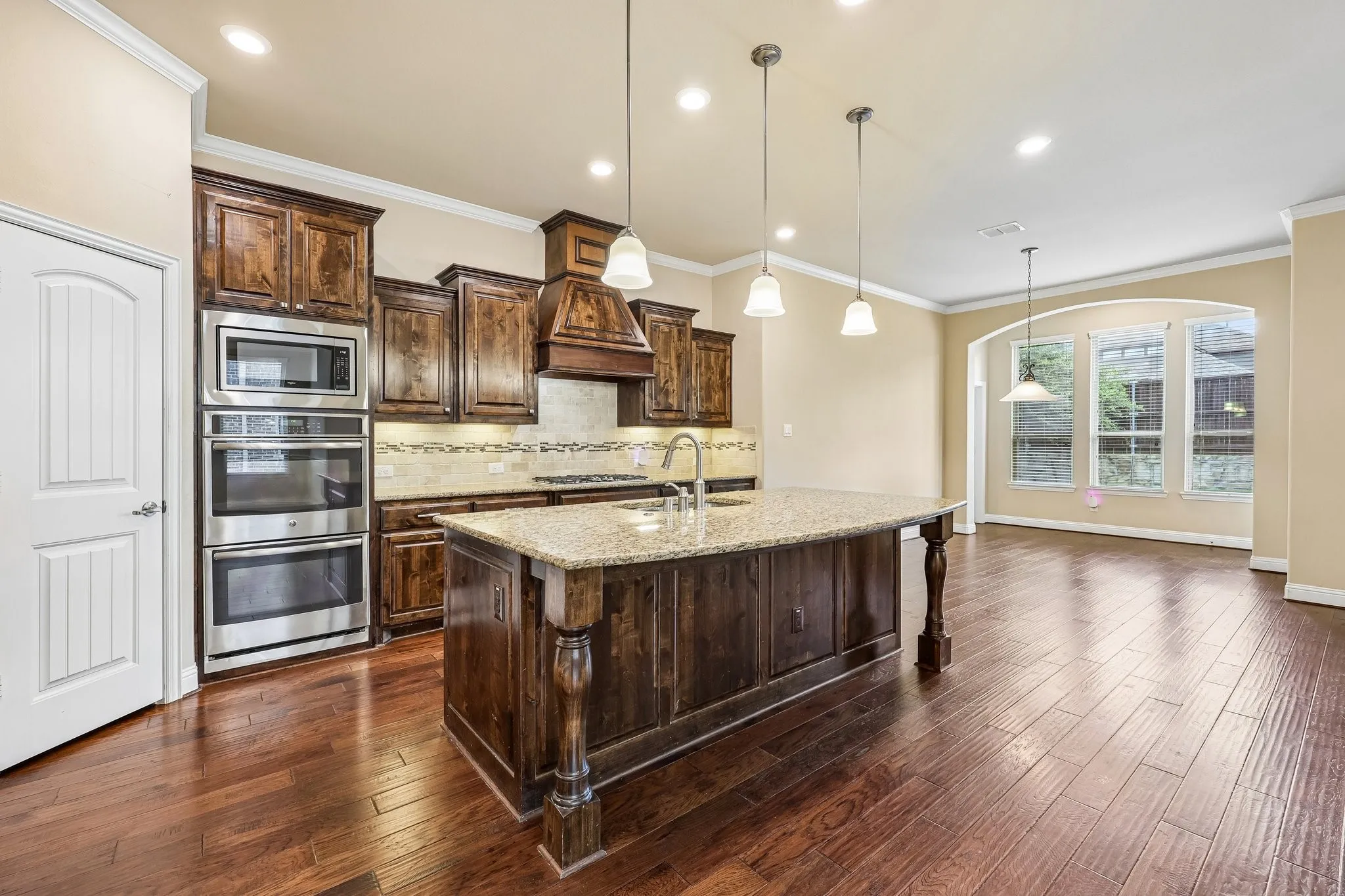 Gourmet kitchen featuring a central island with granite countertop, rich wood cabinetry, stainless steel double ovens, and a built-in microwave