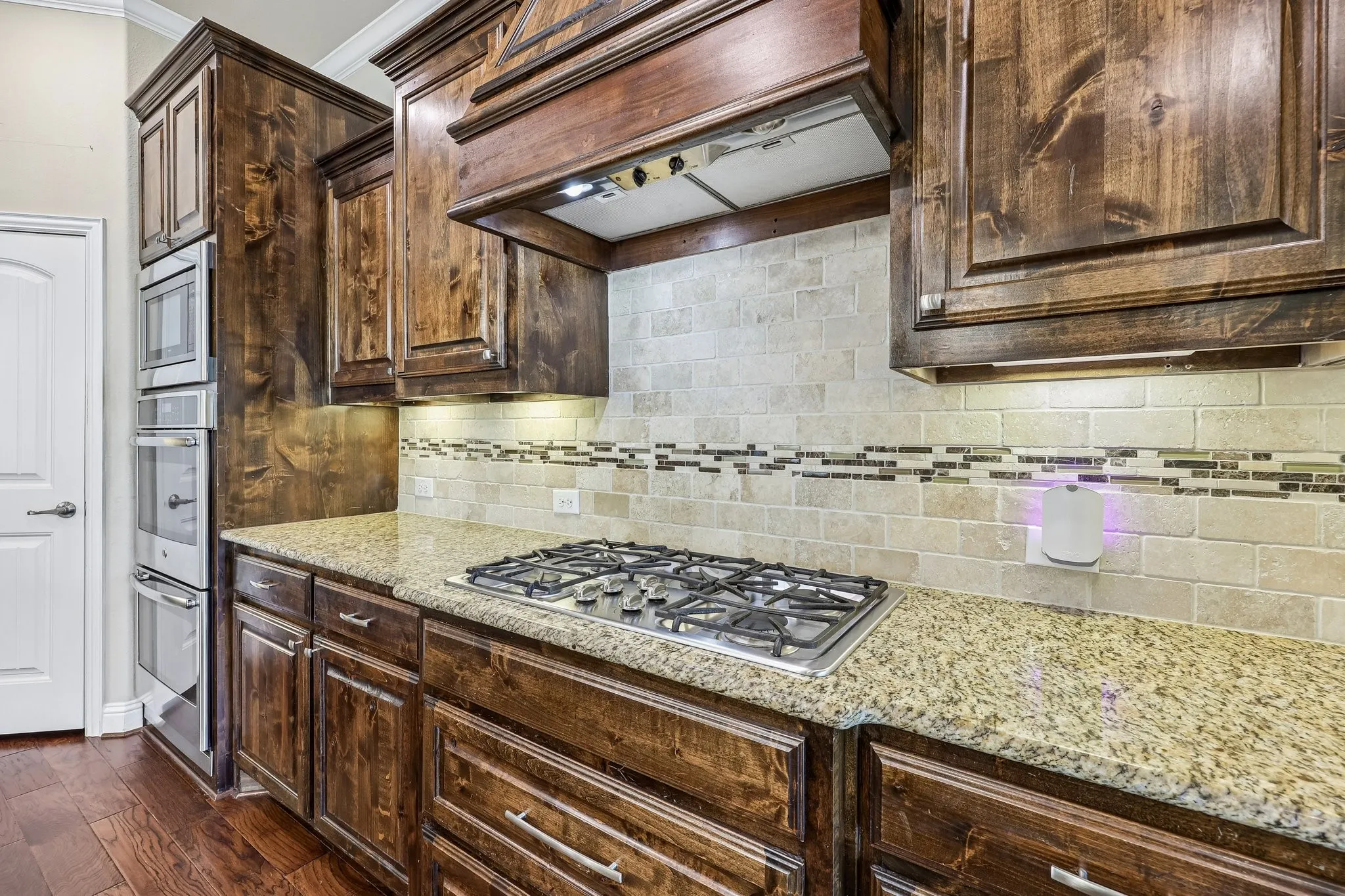 Kitchen featuring rich wood cabinetry, stone countertops, a gas cooktop, and built-in stainless steel appliances