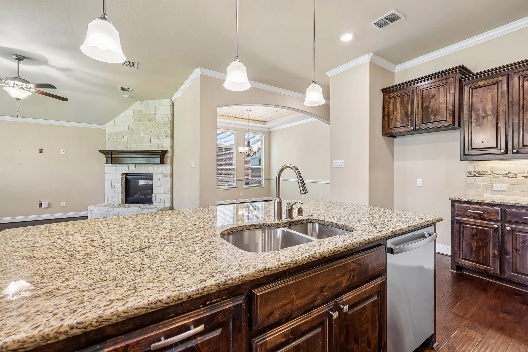 Kitchen island featuring a double basin stainless steel sink, gooseneck faucet, and stone countertop
