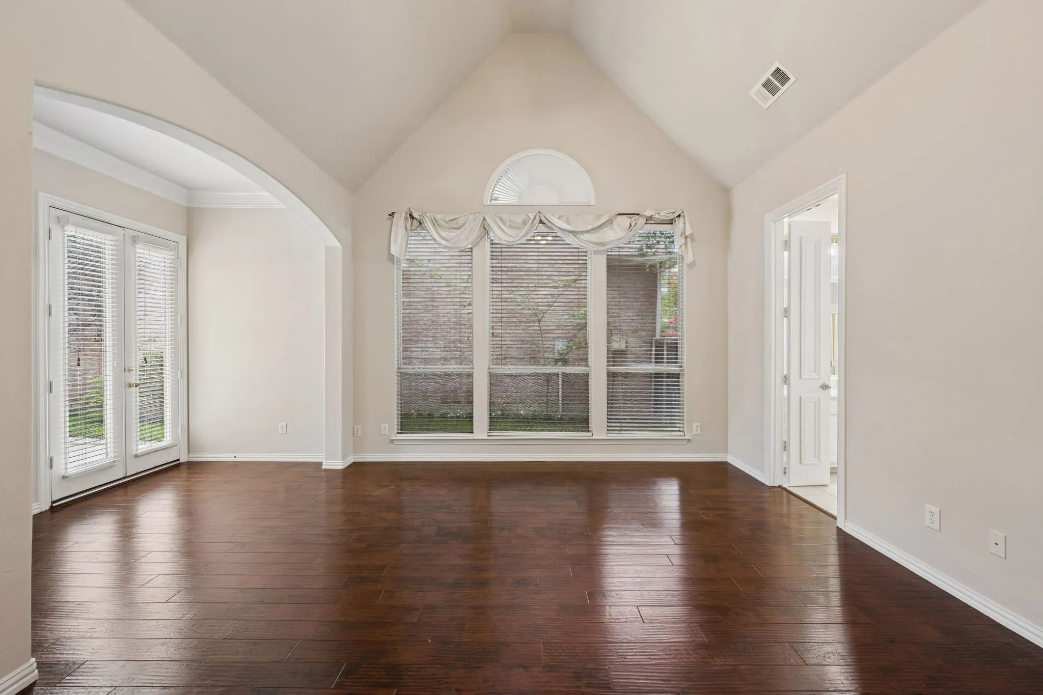 First floor primary bedroom with vaulted ceiling and french doors to side patio