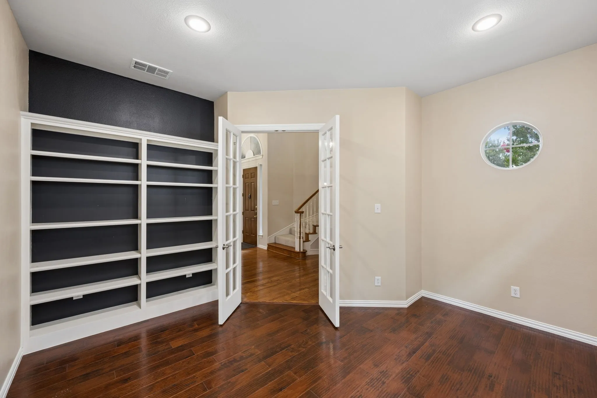 First floor study with built in shelving and french doors to entry hallway