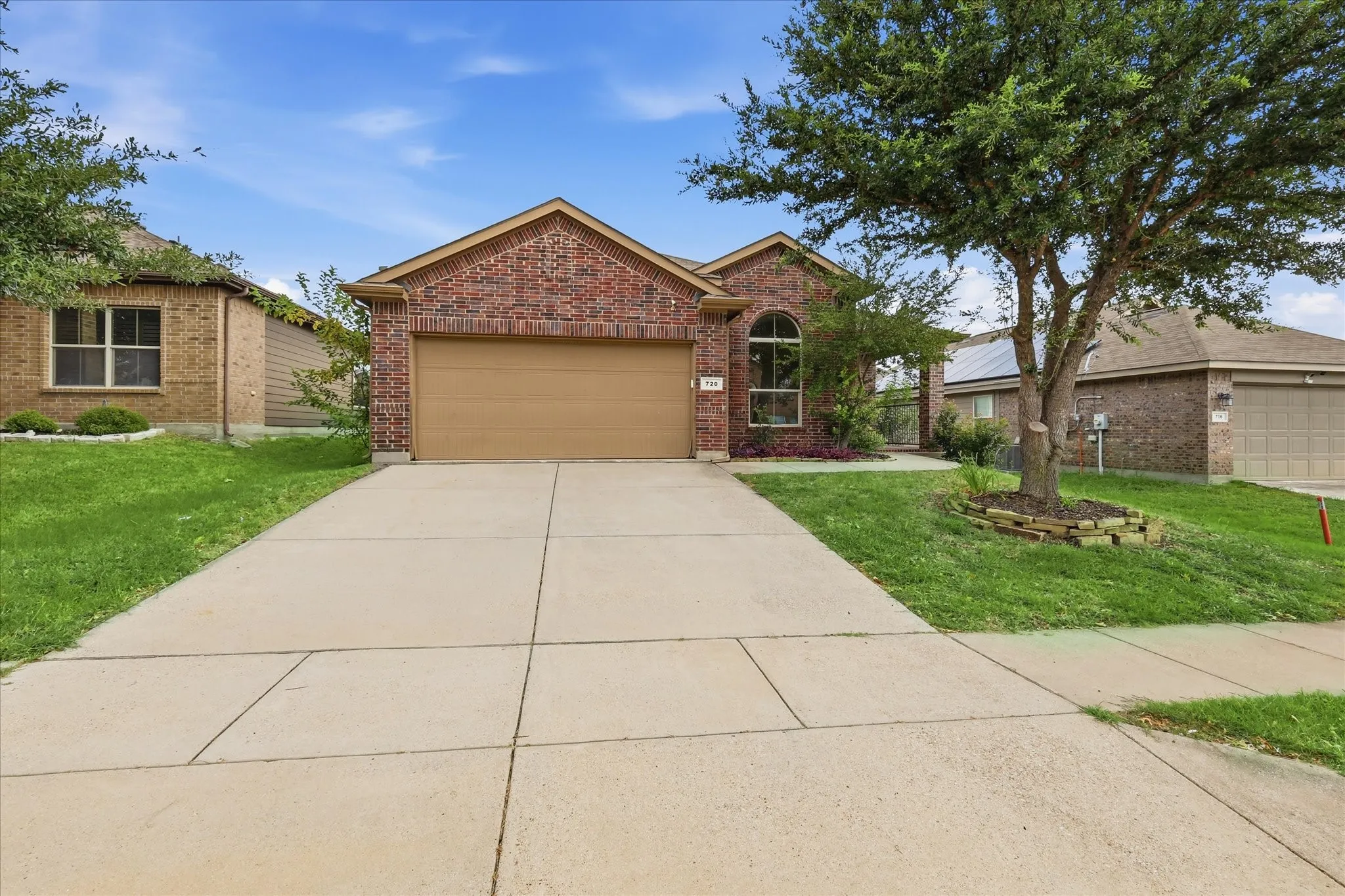 Brick exterior home featuring an arched window, attached garage, and concrete driveway