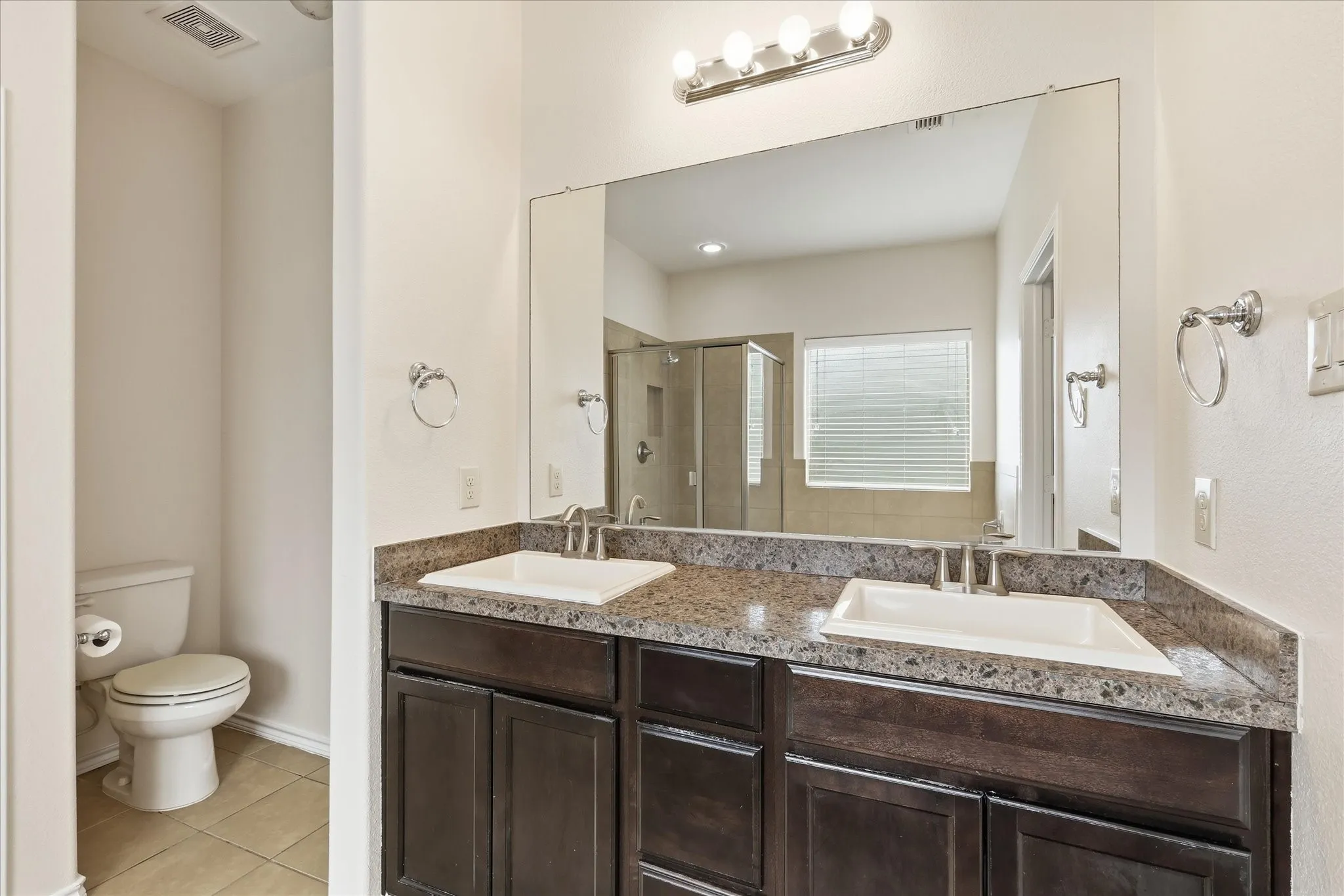 Dual vanity with dark wood-finish cabinetry and light-toned stone countertops