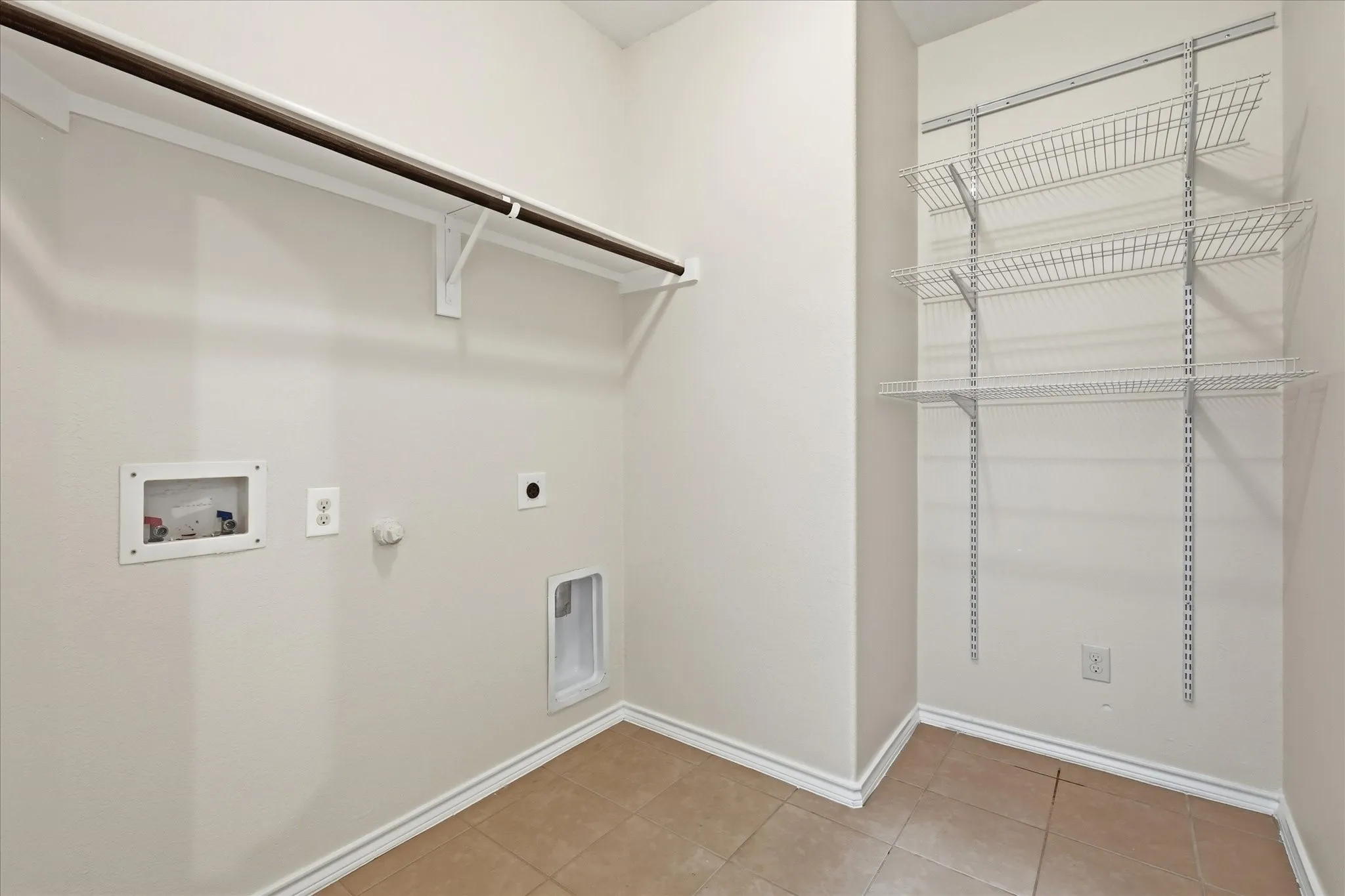 Dedicated utility space featuring a hanging rod, multiple wire shelving units, and tile flooring
