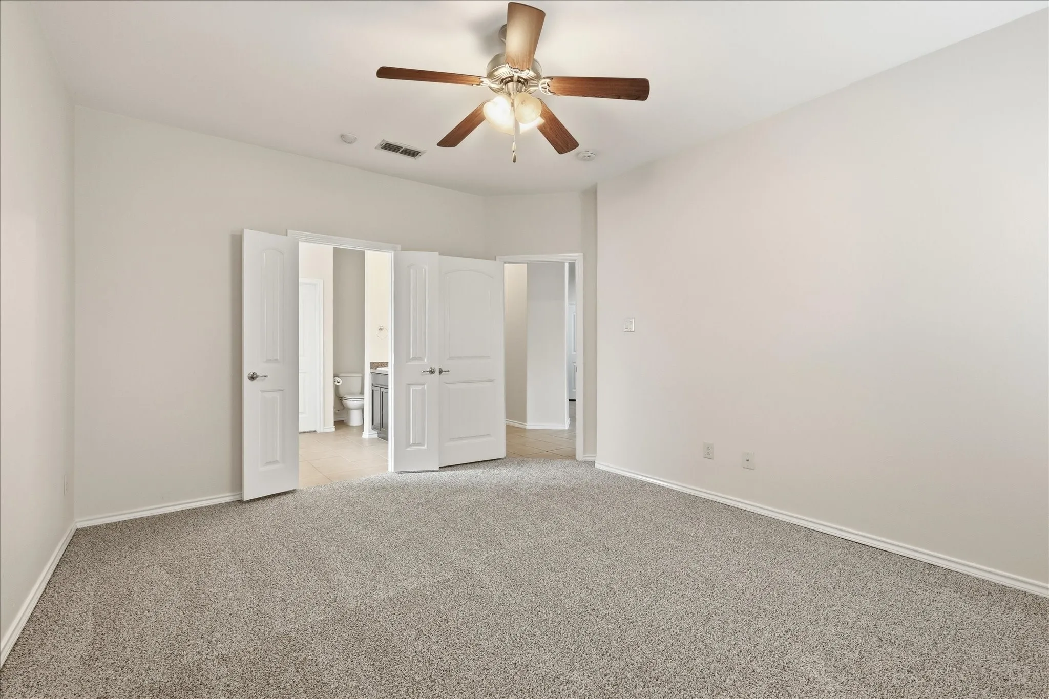Spacious room featuring neutral carpeting, light-toned walls, and a ceiling fan with integrated lighting