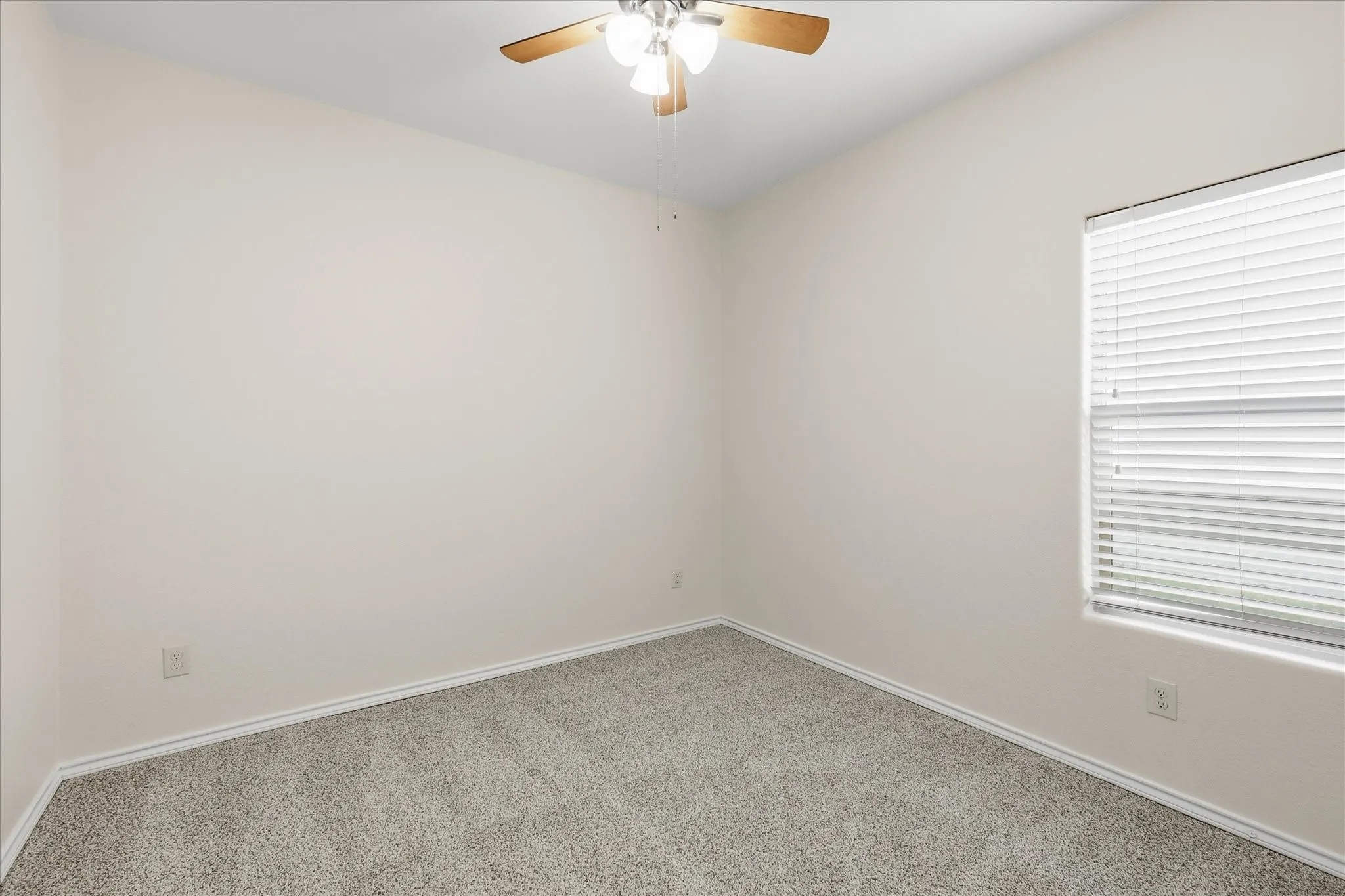 Room featuring neutral wall tones, gray carpet, white trim, and a ceiling fan with light fixture