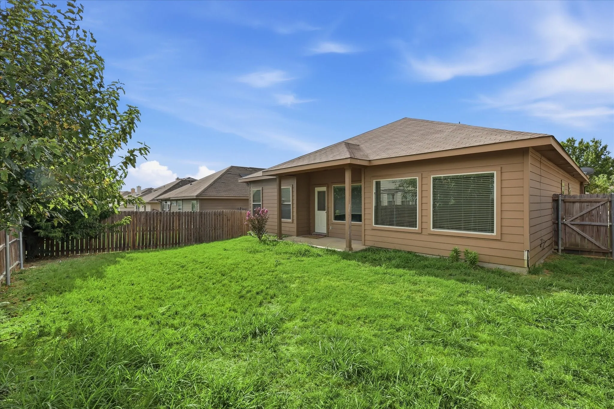 Expansive backyard featuring a partial privacy fence and mature landscaping