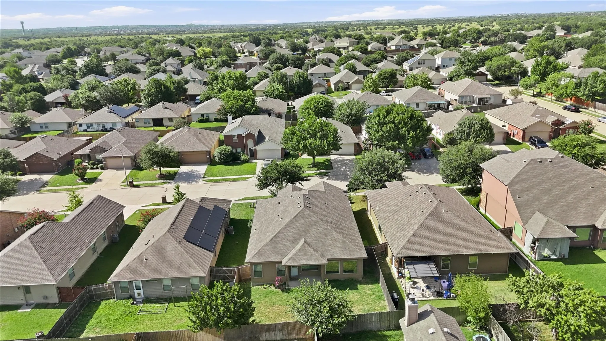 Residential neighborhood featuring established homes with composite shingle roofs, mature trees, and fenced rear yards