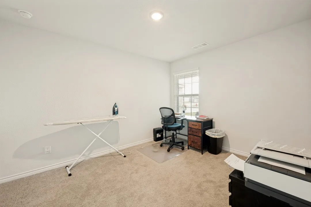 Carpeted room featuring a single window with horizontal blinds, recessed ceiling lighting, and crisp white walls