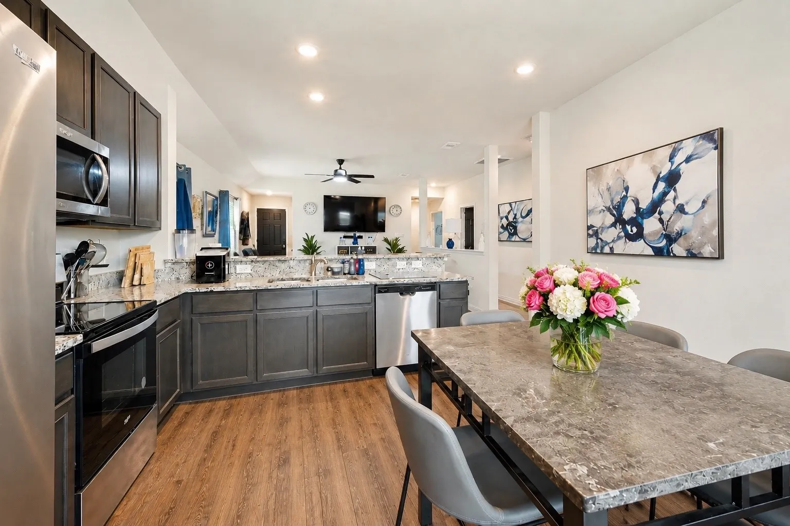 Spacious kitchen featuring dark wood cabinetry, stainless steel appliances, speckled countertops, and wood-finish flooring
