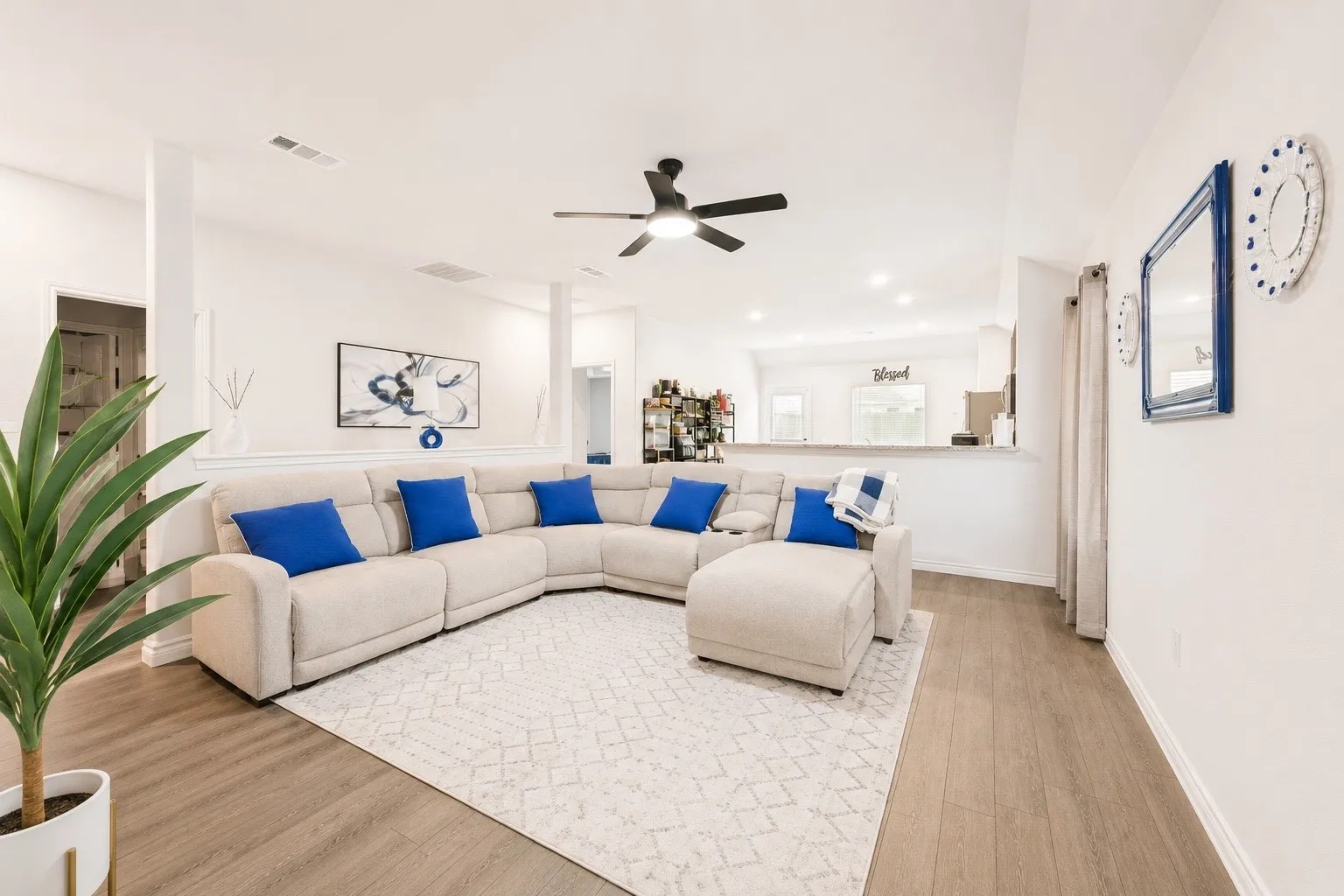Open-concept living area featuring light wood-finish flooring, white walls, a ceiling fan, and recessed lighting