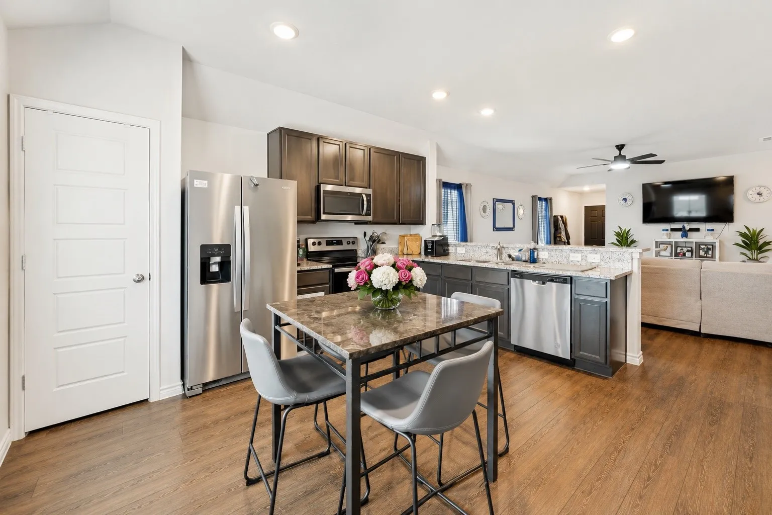 Kitchen featuring stainless steel appliances, dark wood cabinetry, and light-toned countertops