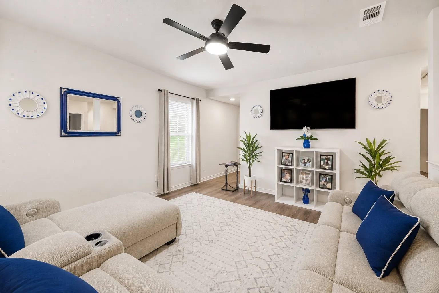 Spacious living area featuring contemporary wood-finish flooring and a ceiling fan with integrated lighting