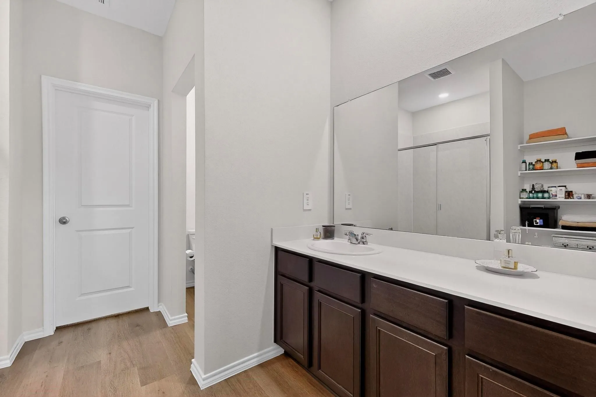 Bathroom vanity featuring a single undermount sink, a white countertop, and dark wood cabinetry