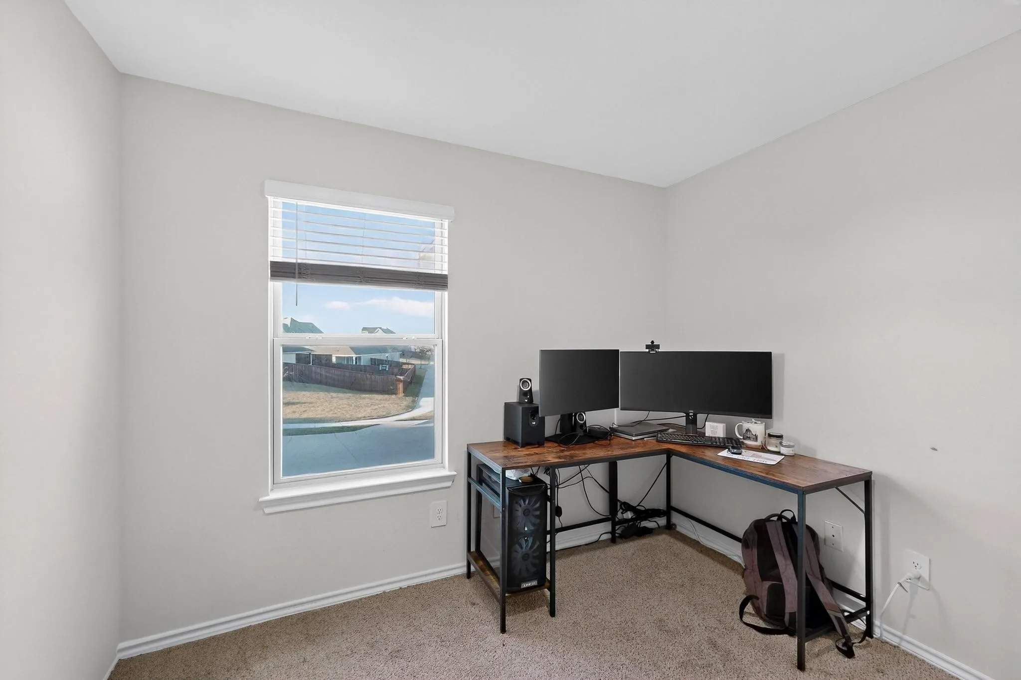 Neutral painted walls with white trim, a single window with white blinds, and light brown carpet