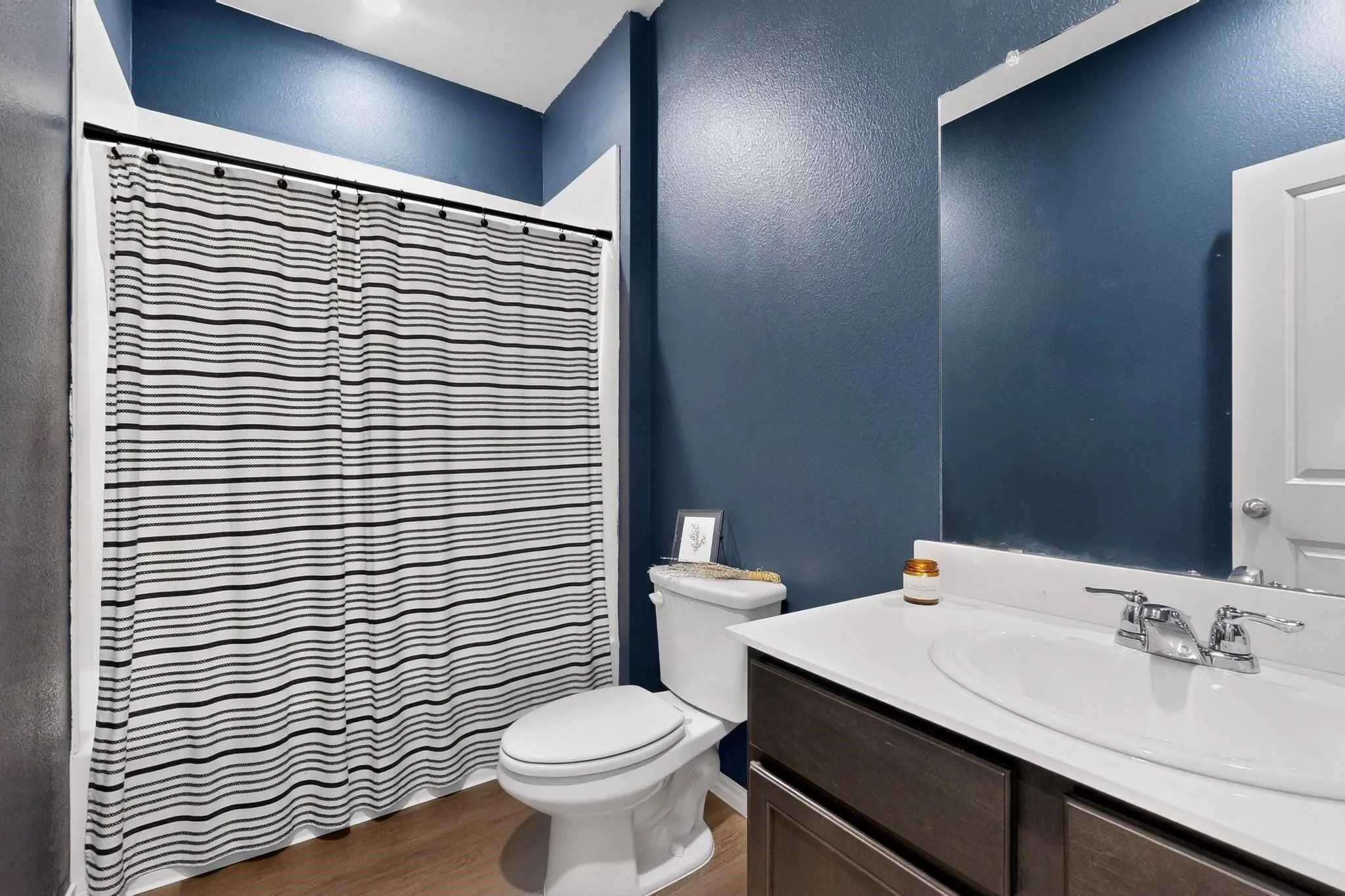 Bathroom featuring a dark wood-finish vanity with an integrated sink, polished chrome faucet, and a wall-mounted mirror