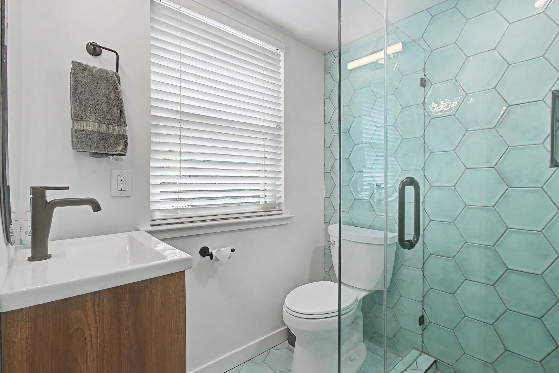 Bathroom featuring a glass-enclosed shower with hexagonal aqua tiling