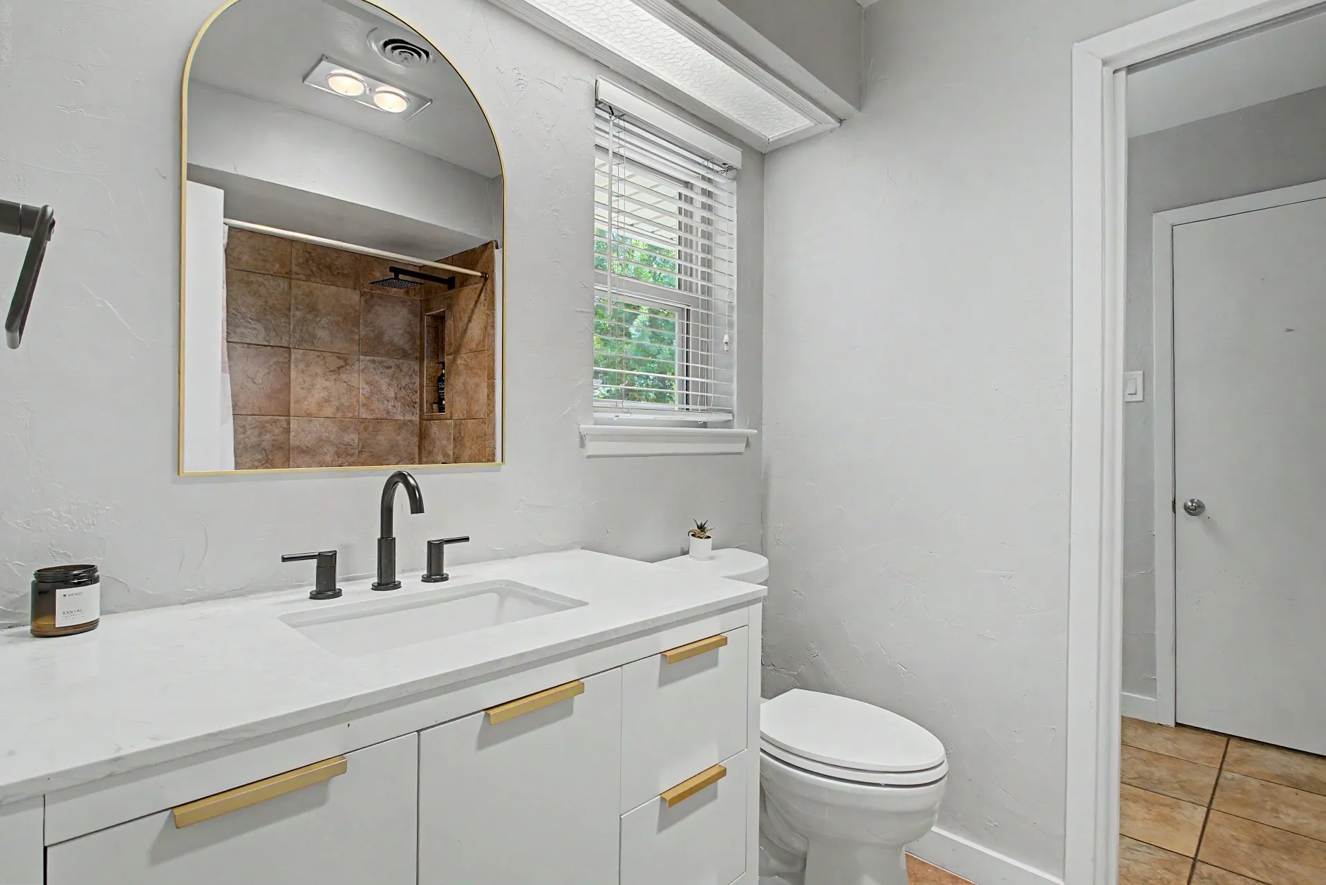 Bathroom featuring a white vanity with gold-tone hardware, a rectangular integrated sink, and a matte black faucet