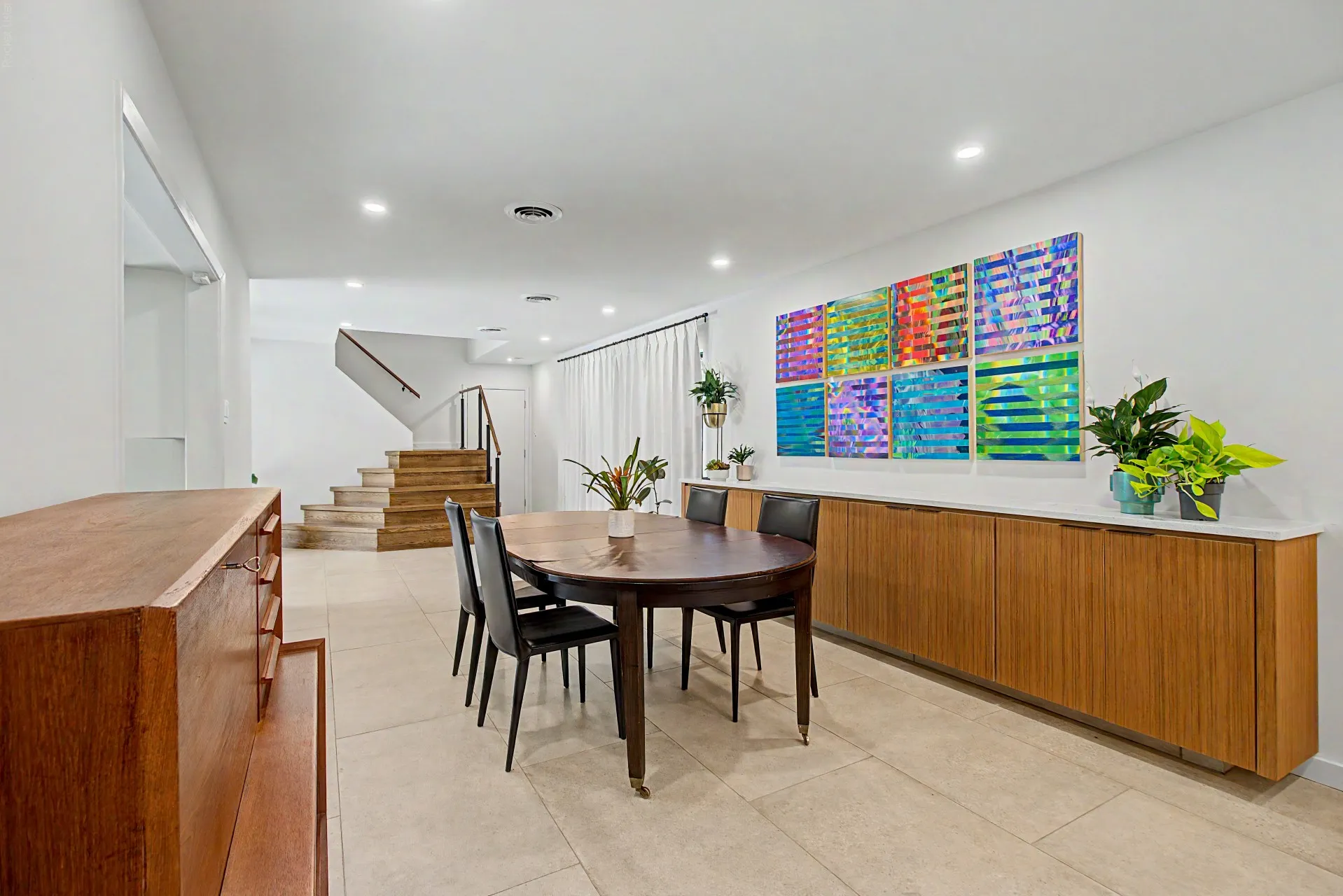 Spacious room featuring neutral tile flooring, recessed lighting, and a prominent built-in wood-finish cabinetry with a light-toned countertop