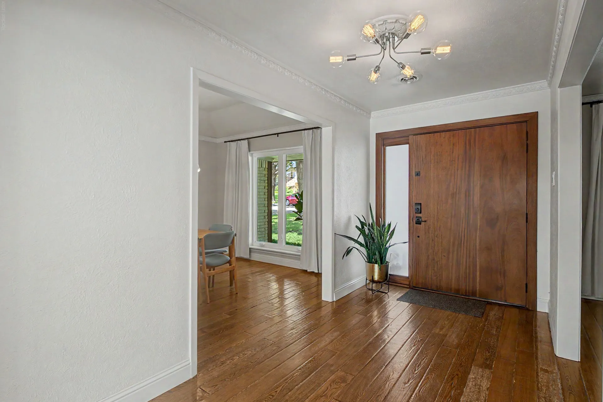 Entryway featuring a solid wood front door with a sidelight, wood-finish flooring, and a modern ceiling light fixture