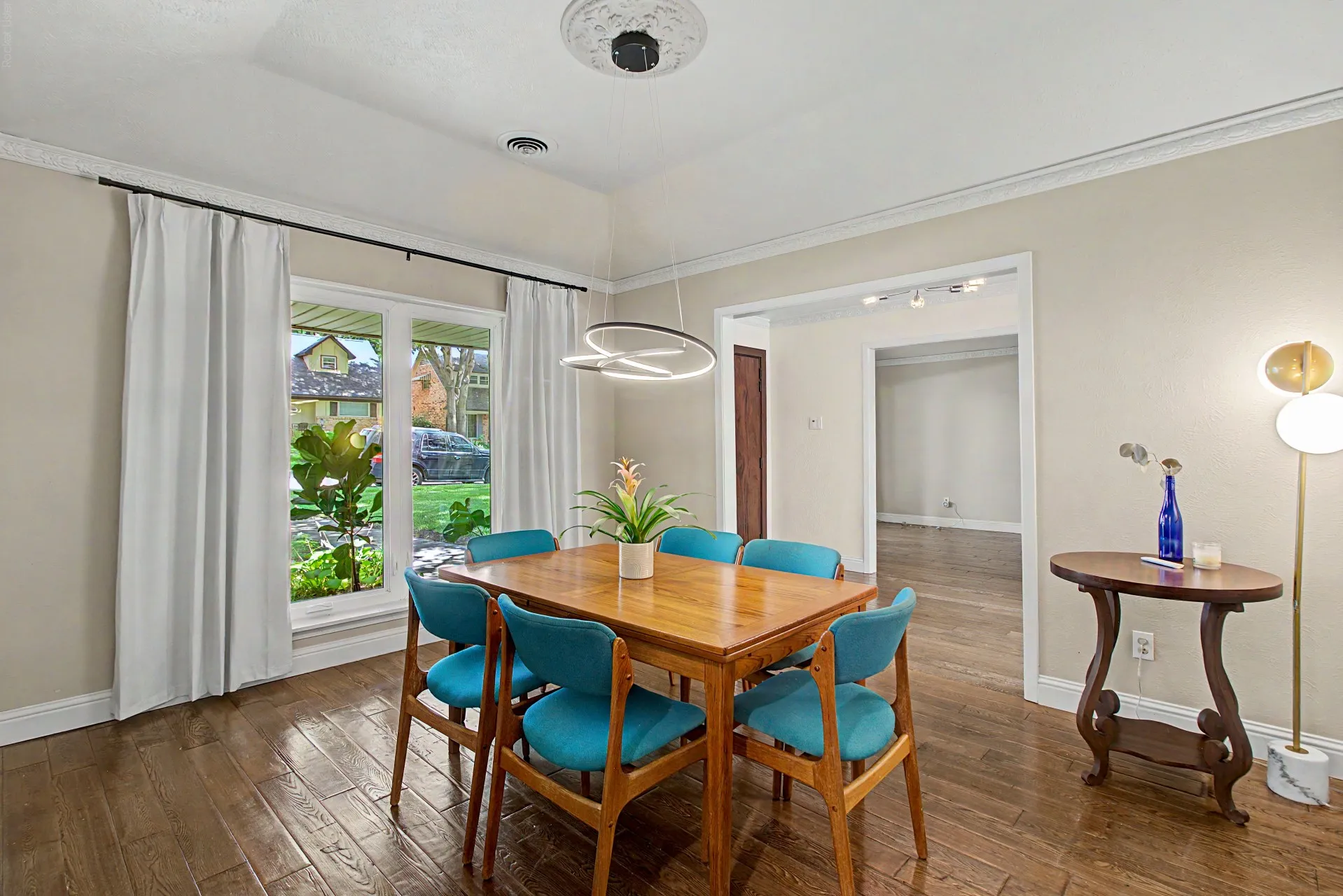 Formal dining area featuring wood-finish flooring, a large picture window, crown molding, and a contemporary ceiling light fixture