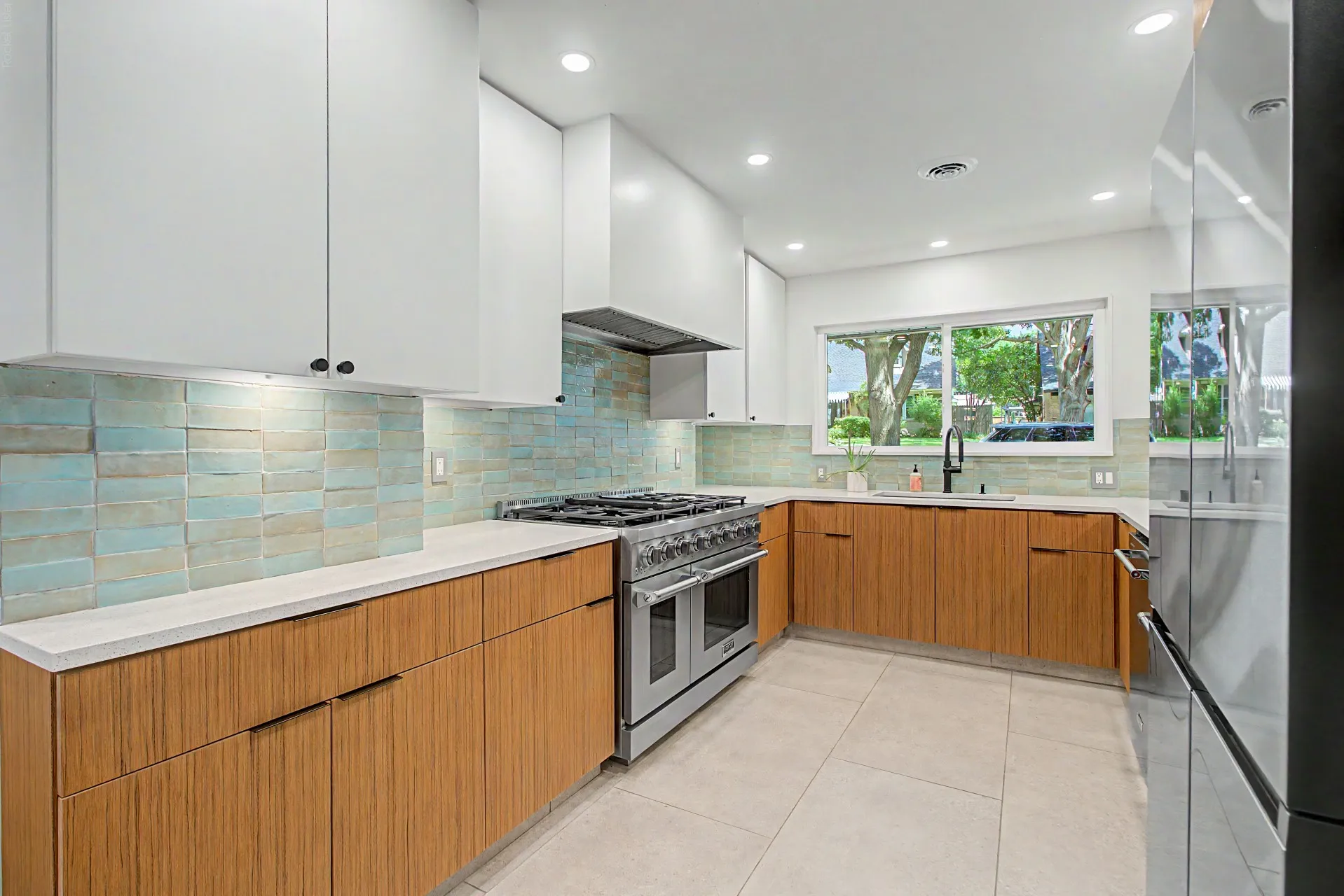 Modern kitchen featuring two-tone cabinetry, a professional-grade gas range, and a full-height tile backsplash