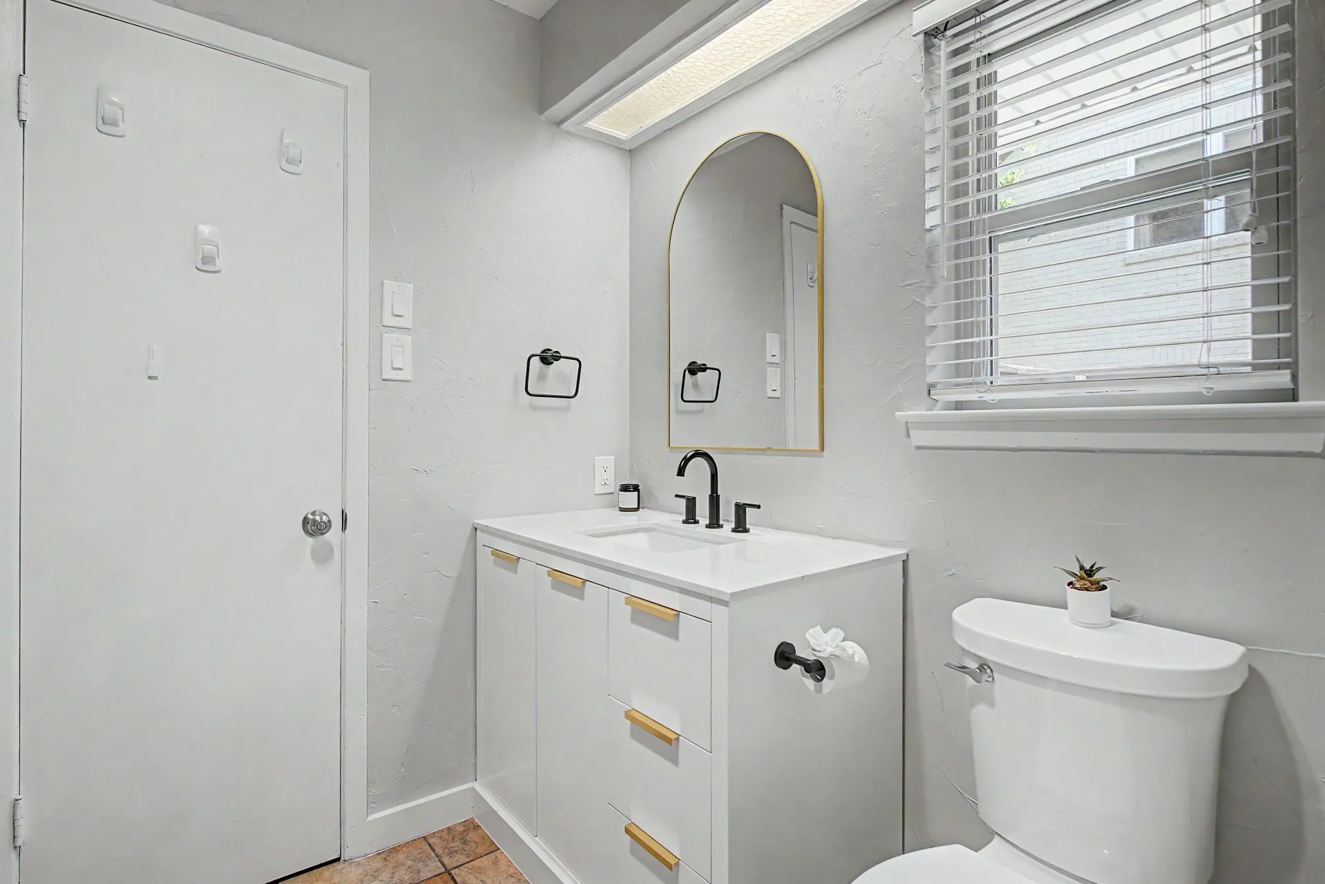 Bathroom featuring a white vanity with gold-tone hardware, a rectangular sink, and a matte black faucet