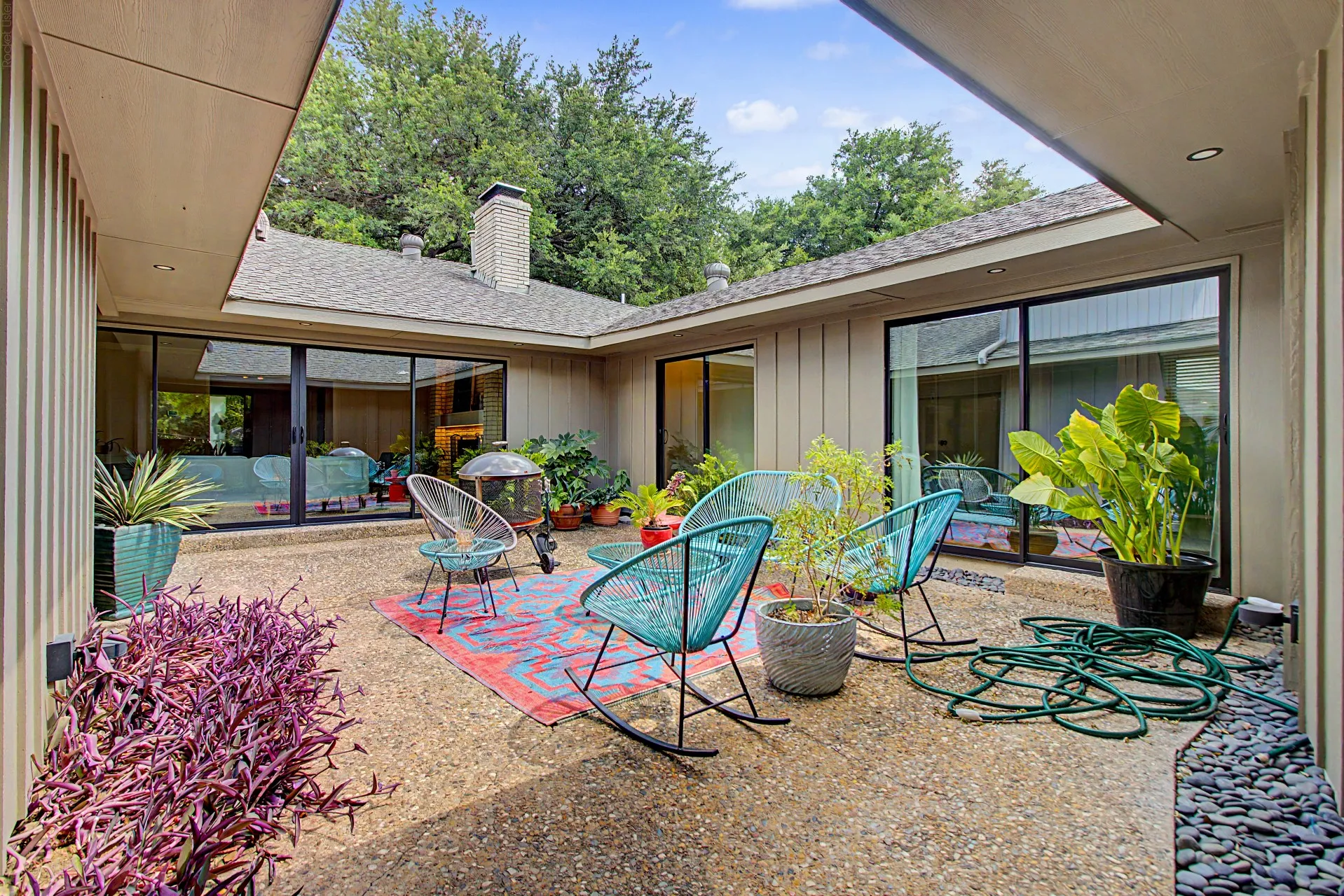Spacious courtyard featuring exposed aggregate paving, a rock garden accent, and mature landscaping