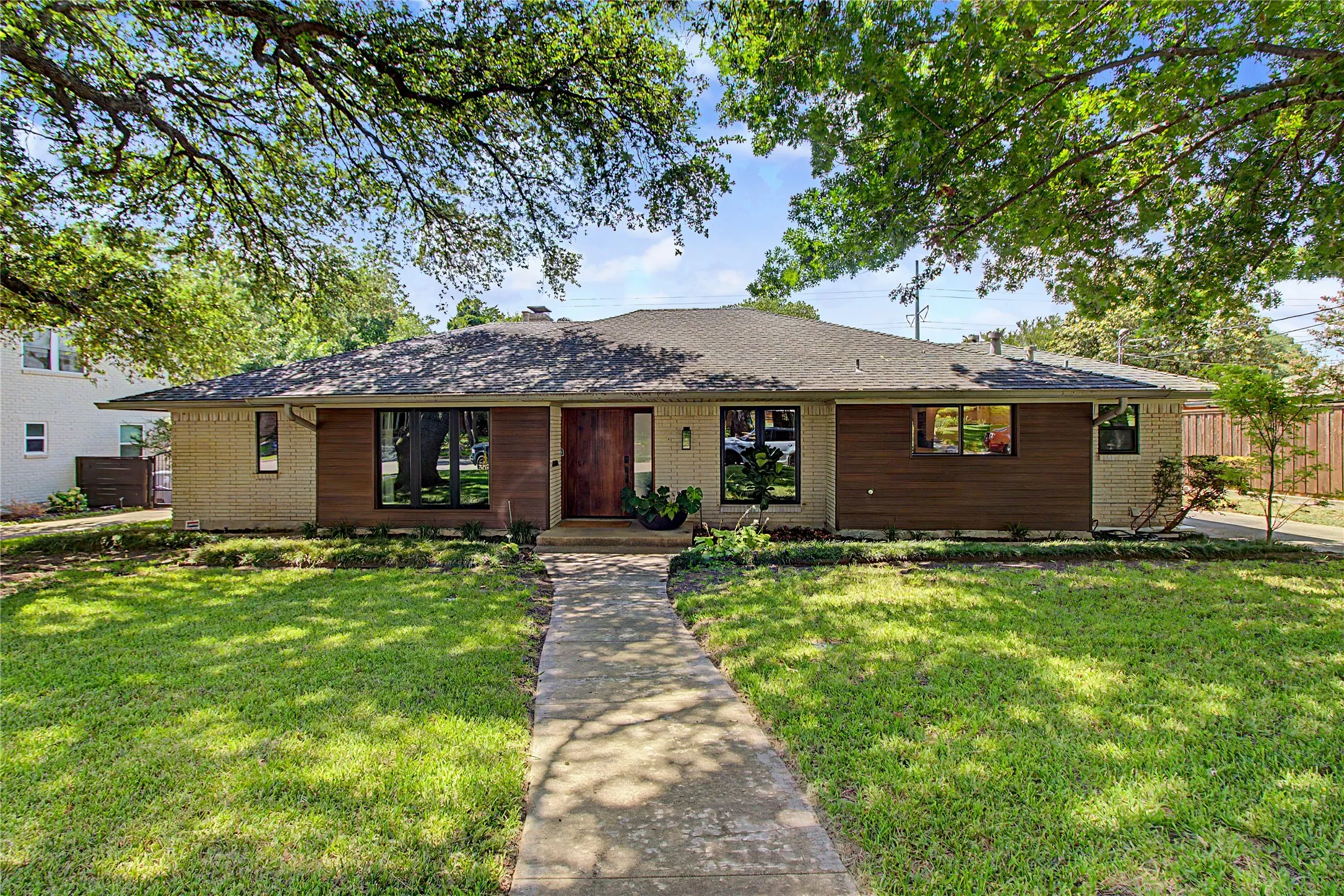 Ranch-style residence featuring a combination of light-colored brick and horizontal wood-finish siding