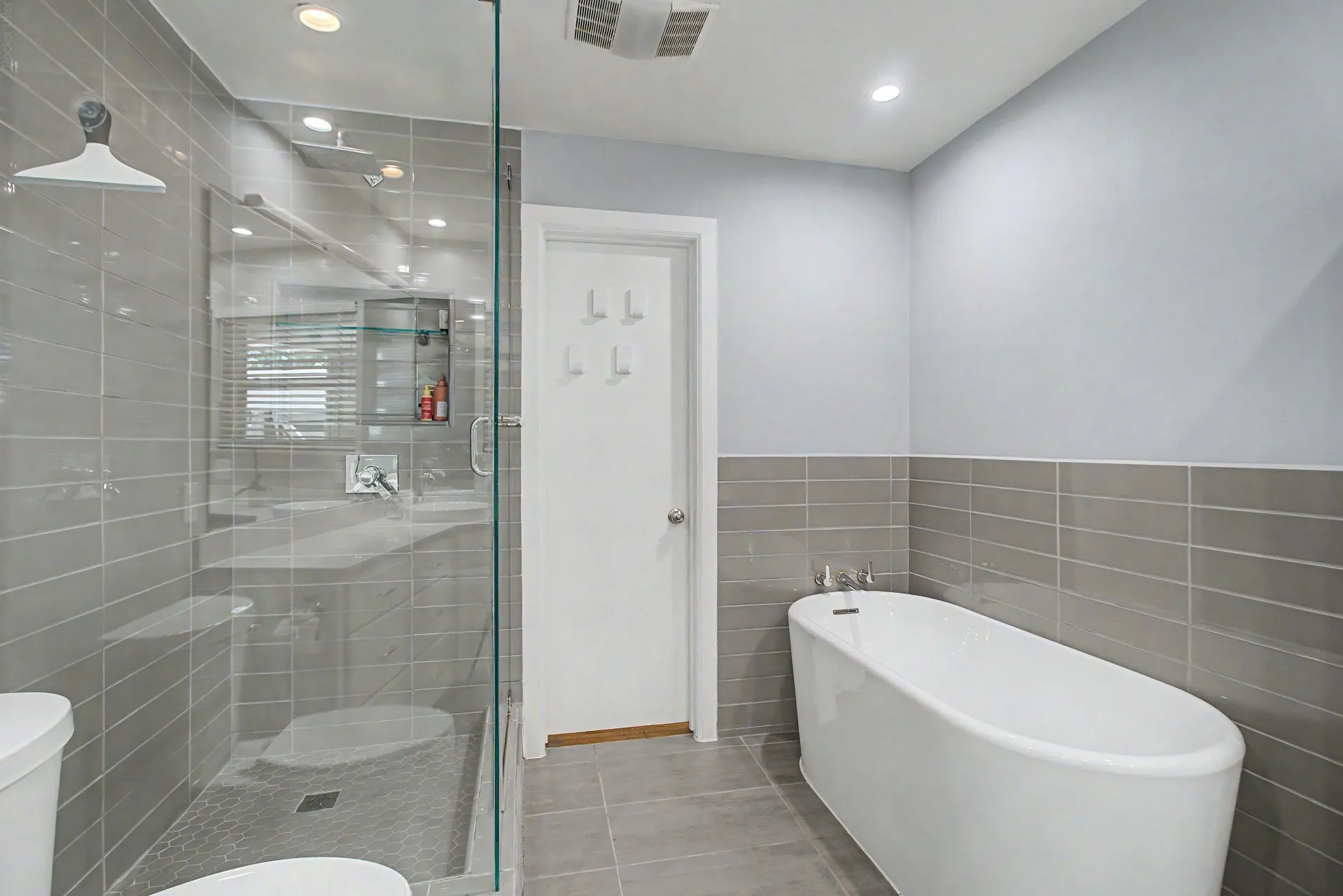 Modern bathroom featuring a frameless glass shower enclosure, a standalone soaking tub, and contemporary gray tile flooring
