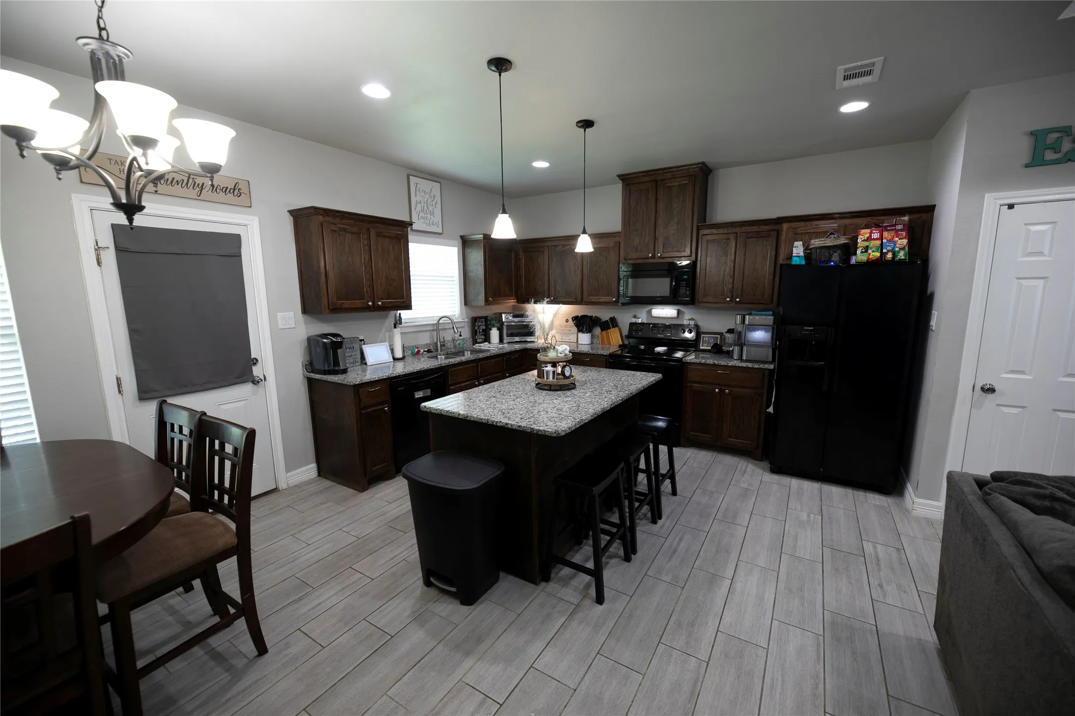 Contemporary kitchen featuring rich wood cabinetry, granite countertops, and light wood-finish flooring