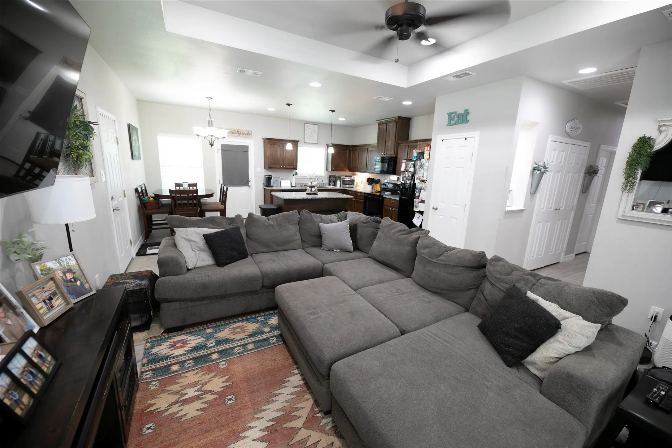 Open-concept living area featuring a tray ceiling with a ceiling fan, recessed lighting, and light-toned walls